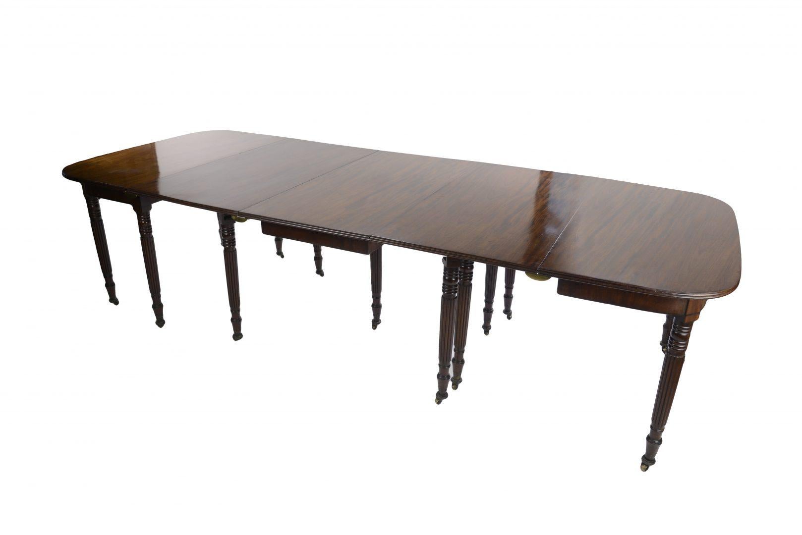 A fine George III mahogany extending dining table, attributed to Gillows. The three section rectangular top with rounded corners and fluted edges comprising a drop leaf centre section and two D ended end sections, one extra leaf, raised on thirteen