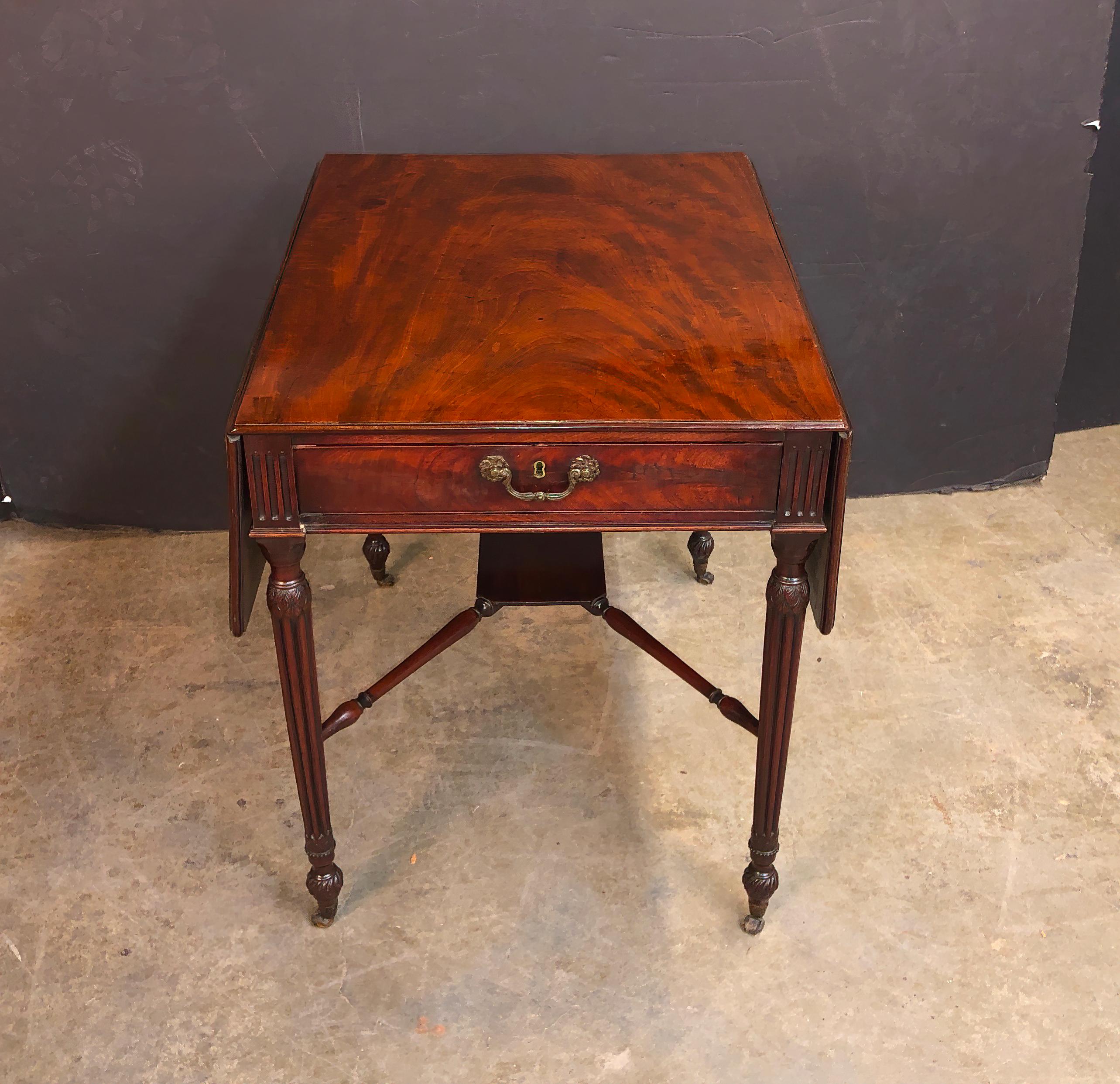 A fine English mahogany Pembroke table with beautifully figured mahogany, a molded edge, with single drawers, on leaf, carved and turned and fluted legs with an X-stretcher, twisted and reeded feet and raised on casters.