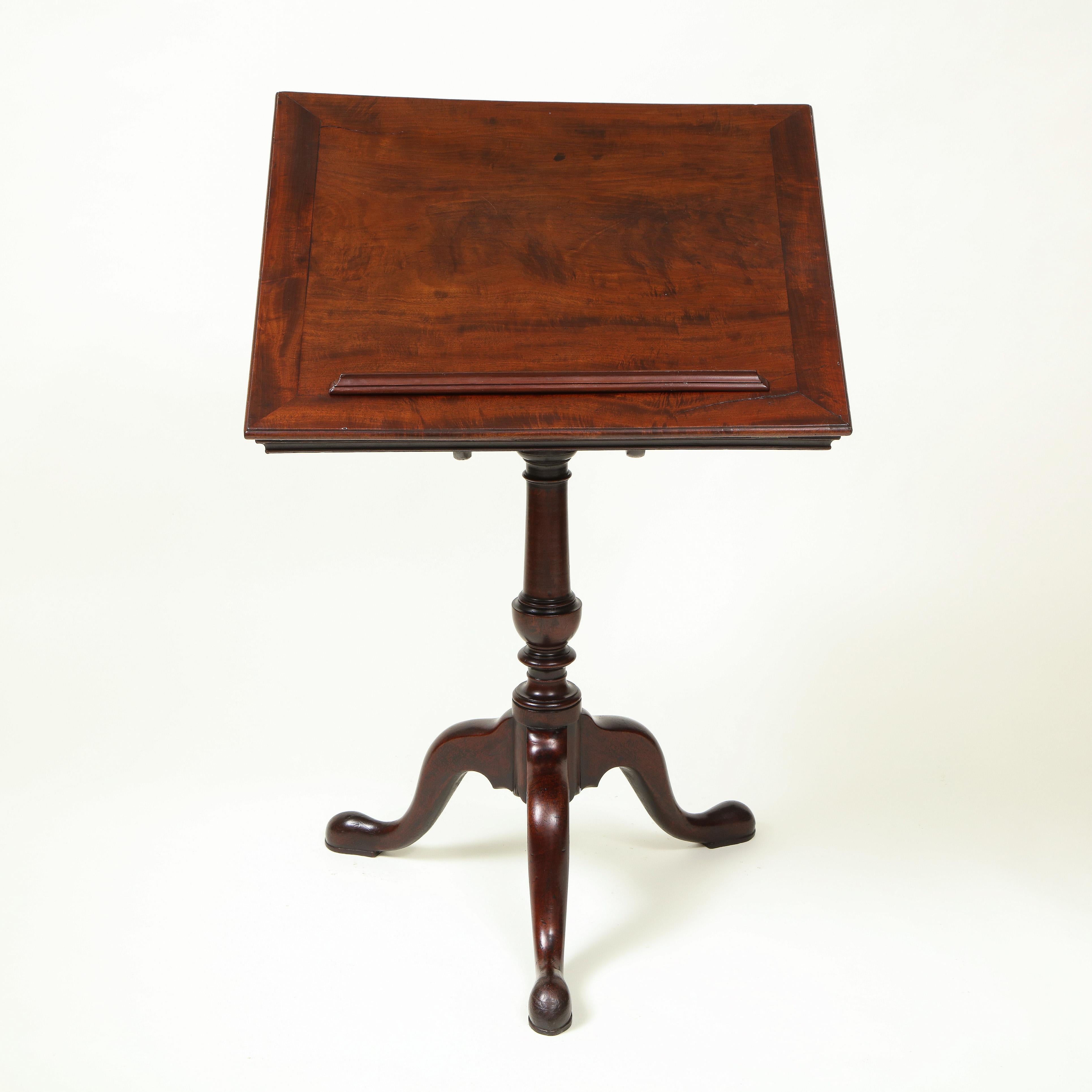 The rectangular tilt-top of finely figured timber with removable reading ledge; raised on a turn columnar support and three downswept cabriole legs terminating in pad-form feet.

Provenance: From the Collection of Mario Buatta, New York, NY.