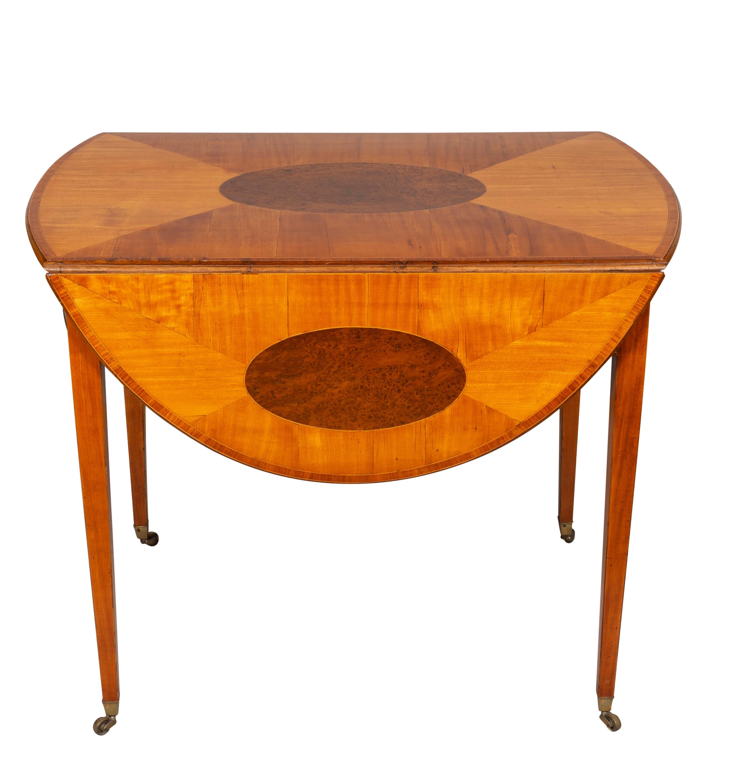 Rectangular top with D shaped hinged leaves, the center and leaves with oval inlay over a frieze containing a conforming drawer with a pair of brass handles and an opposing identical false drawer, raised on square tapered legs and casters.