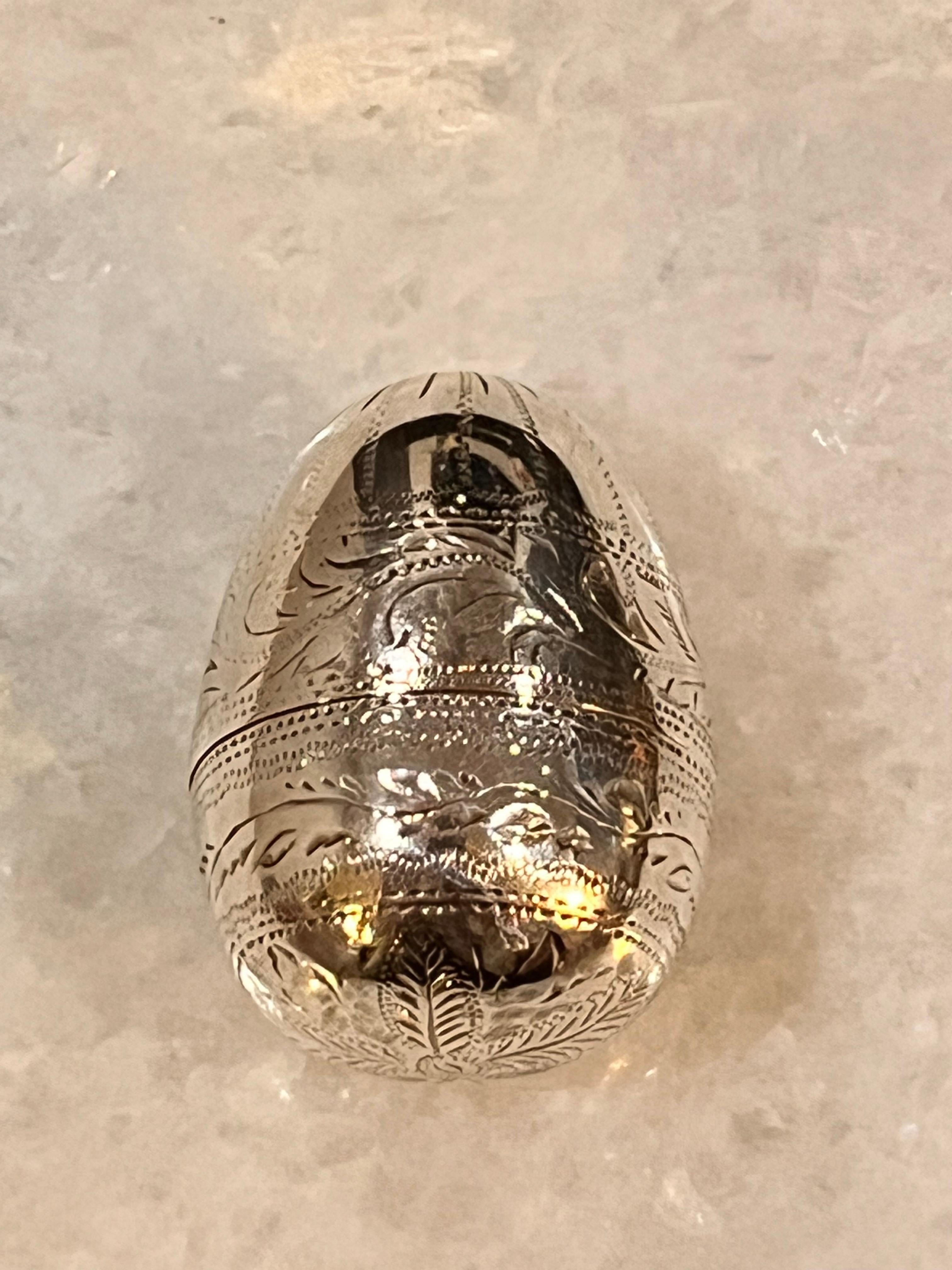 A George III silver egg form nutmeg grater, the exterior finely decorated with bright cutting depicting foliate scrolls, with the tapering end decorated with intricate fluting. The detachable cover is similarly decorated and surmounted by a quartet