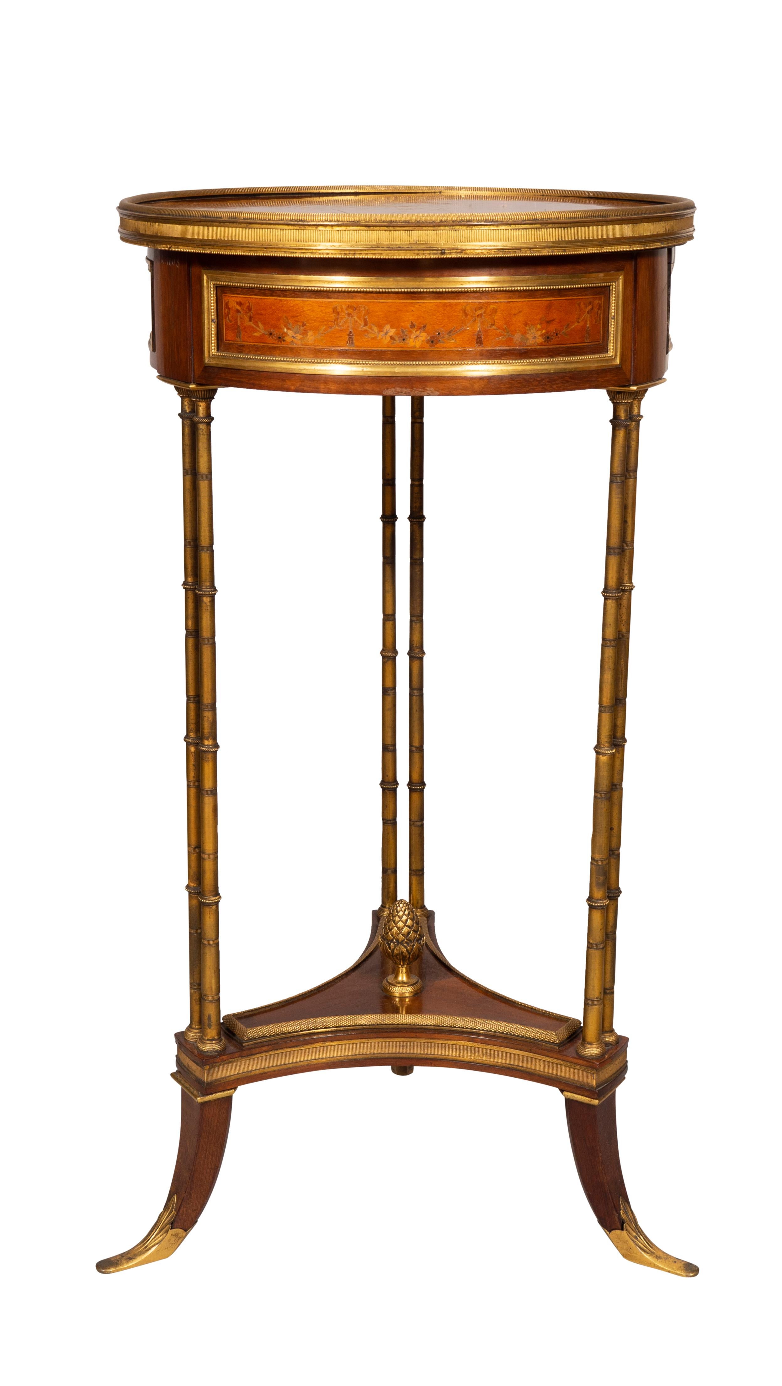 Circular top with central floral spray and rosewood banding and bronze edge, the frieze with a drawer with hidden button to open. The whole frieze with floral inlays, raised on bronze cluster legs joining a mahogany stretcher with bronze finial,
