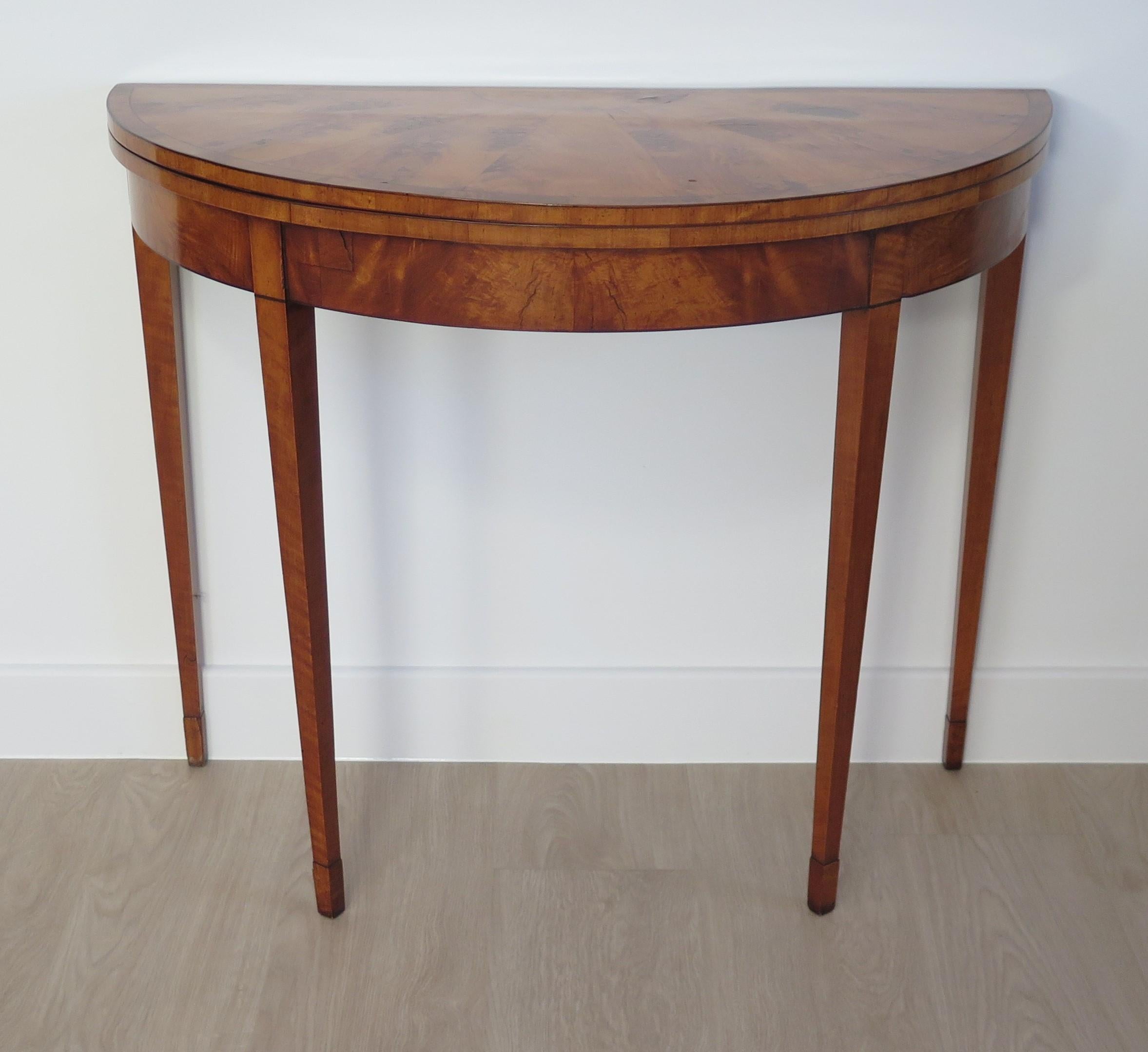 A very beautiful and elegant Georgian Sheraton Period, fold over Demi-Lune card or games table in Satinwood, Circa 1790. 

This is a semi circular (demi-lune) fold over table made of Satinwood and carefully chosen Satinwood veneers, with Kingwood