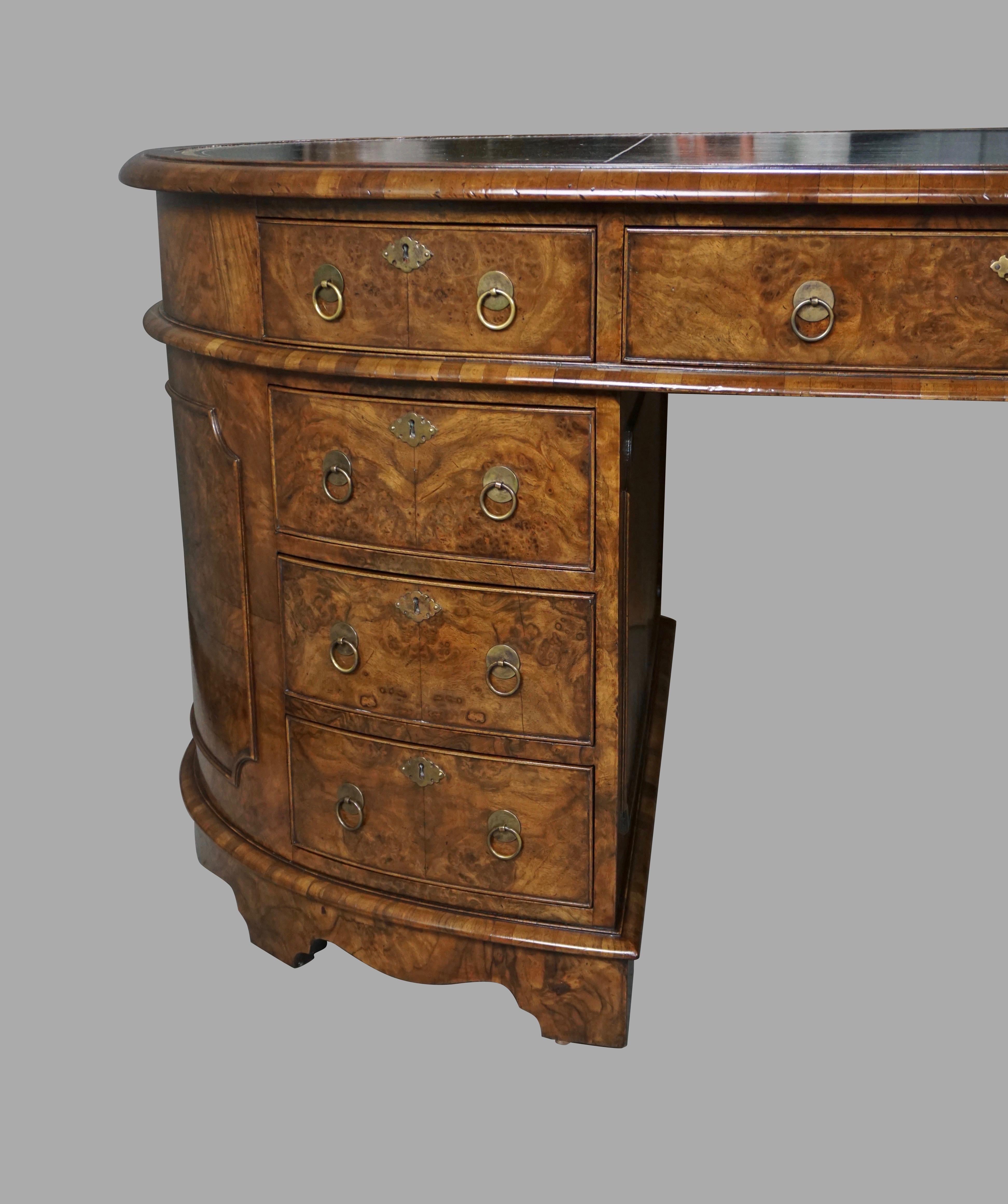 An elegant and unusual English burl walnut oval partners desk, the inset green tooled leather top with a molded edge above one long and 2 short drawers supported on pedestals with 3 further drawers on each side. Reverse is identically configured.