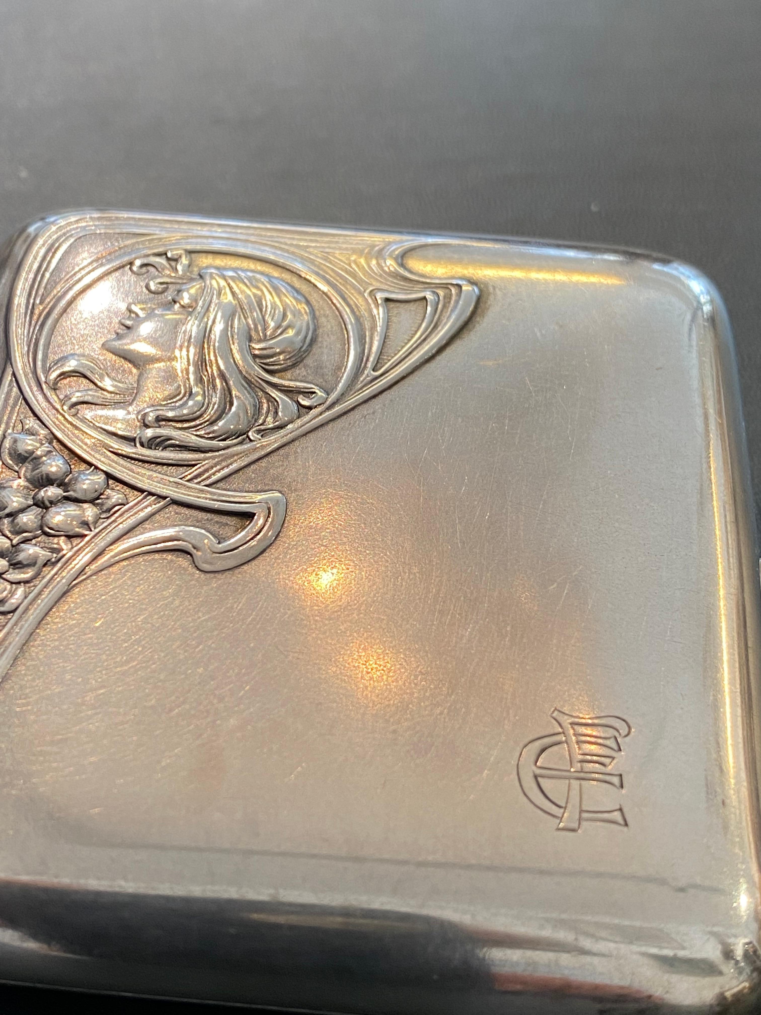 Nice and well preserved cigarette box, showing a young Lady‘s head on the frontside. Hallmarked with the Crown and Moon stamp and made of 800/1000 Fine Silver. Closes fine and smooth and holds. No dongs or bad scratches.
The ribbons ti hold the