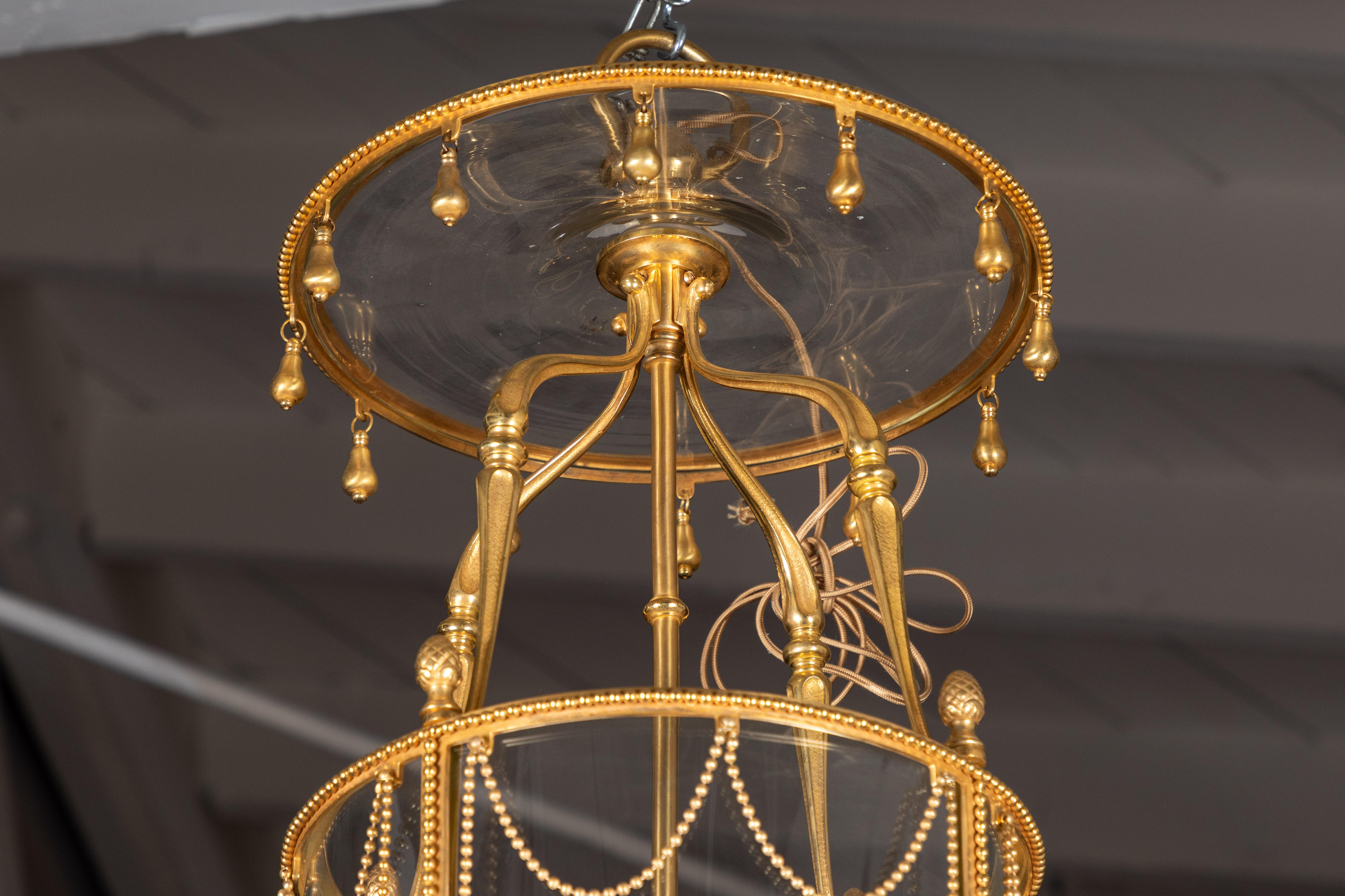 Eine glitzernde, vierflammige französische Kutschenlaterne aus dem 19. Jh. mit einem Rahmen aus Bronze-Doré und einem Baldachin mit vergoldeten Tropfen. Der tonnenförmige Korpus wird von einer Reihe von Kettenbändern gekrönt, die von schön geformten