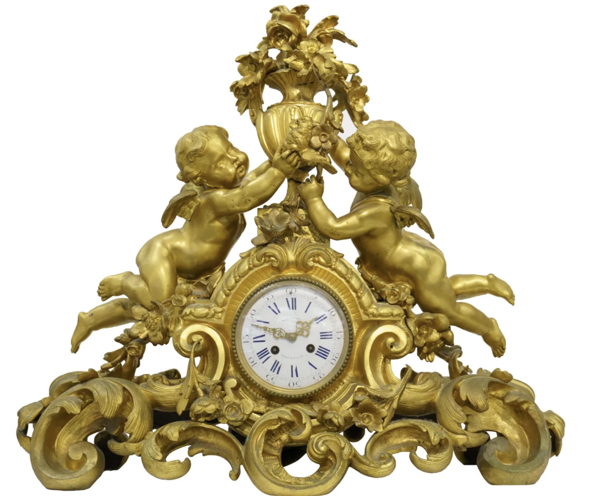 Ornate rocaille scrolled base with garland swags, centered the enamel white clock face with Roman and Arabic Numerals, the face with, G. Philippe, Palais Royal 66, flanked by two putto's holding a urn filled with flowers,

the mechanism stamped G.