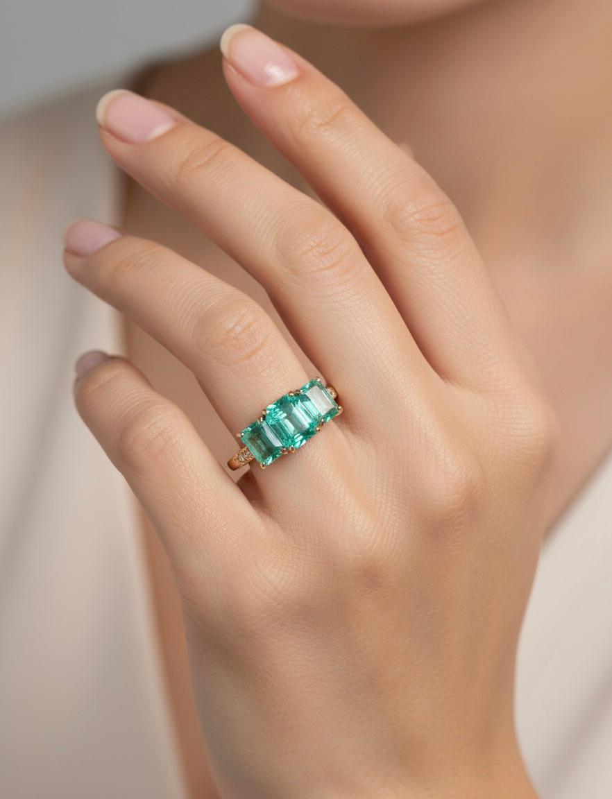 Cette magnifique bague de fiançailles à trois pierres en or 18k comprend au centre une émeraude colombienne de 1,40 ct. mesurant 7,85 x 6,08 mm.  De part et d'autre de cette magnifique pierre, des émeraudes assorties de taille émeraude, totalisant