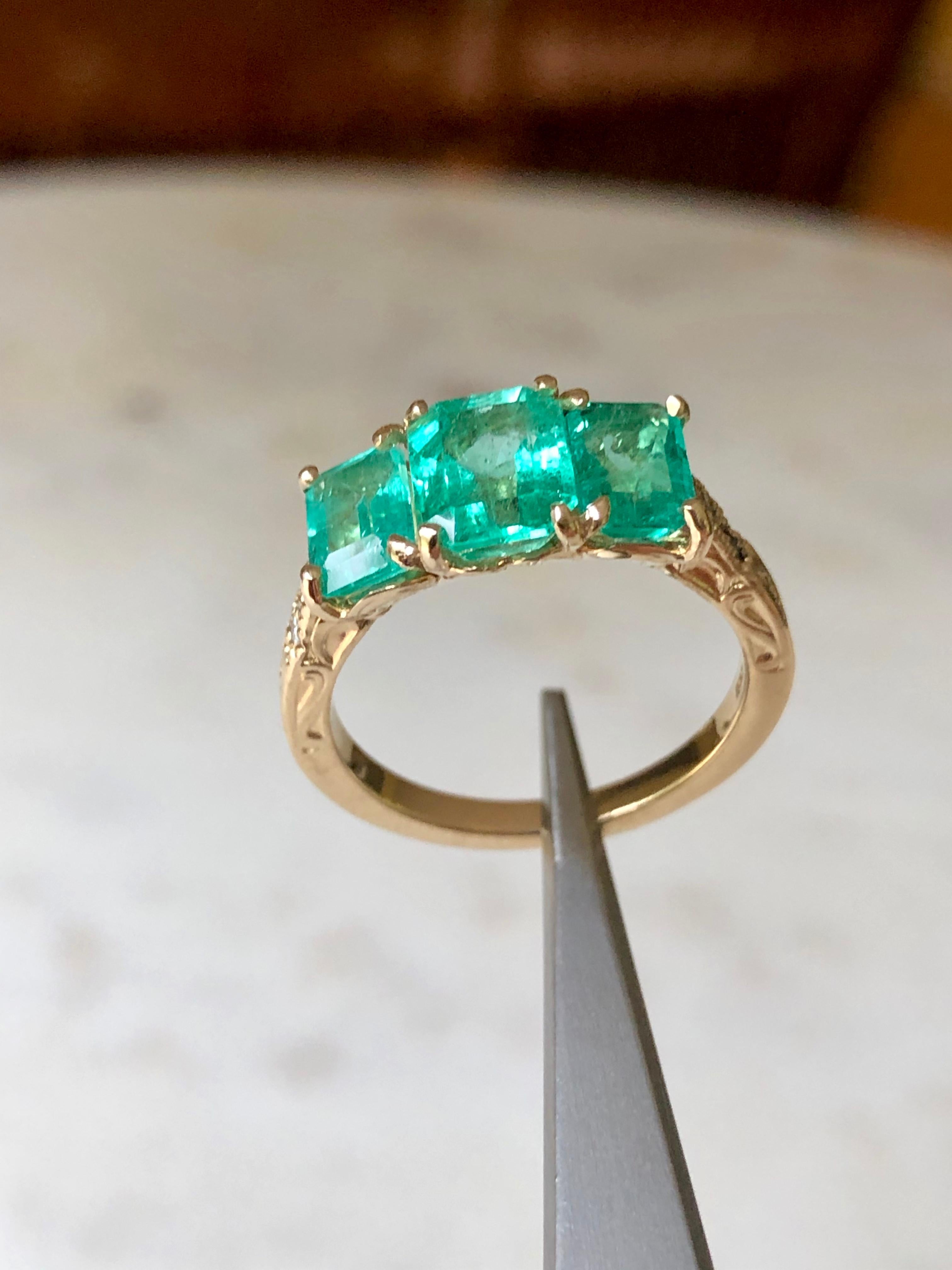 This stunning Colombian emerald 18k gold three stone engagement ring features in center; 1.40ct vs glowing-lustrous Colombian emerald measuring 7.85x6.08mm.  On either side of this beautiful vs stone sits emerald cut matching emeralds, totaling