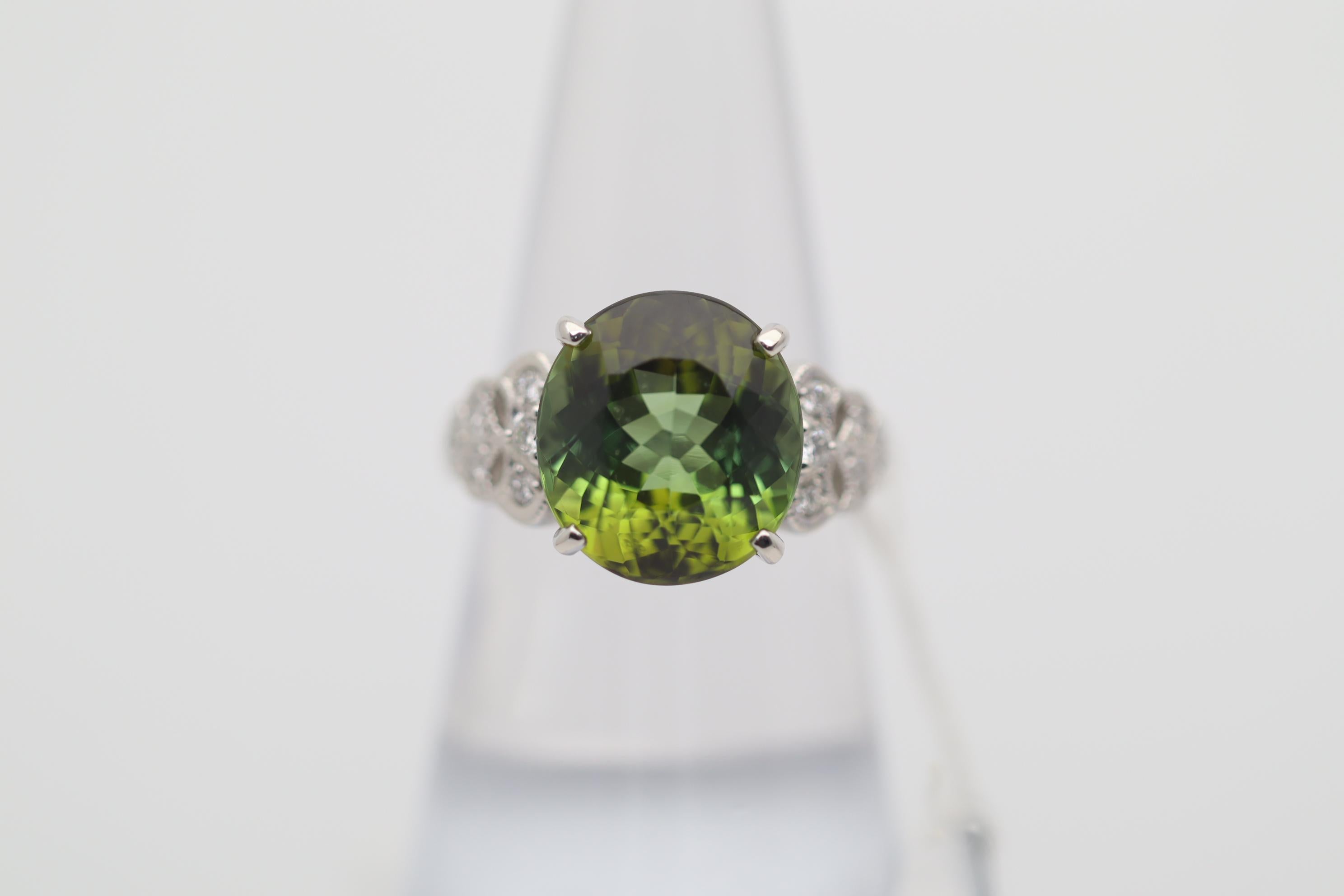 A superb green tourmaline takes center stage of this platinum made ring. It weighs 8.46 carats and has a brilliant, lively, and rich lime green color. It is accented by 0.22 carats of round brilliant-cut diamonds set on the sides of the ring.