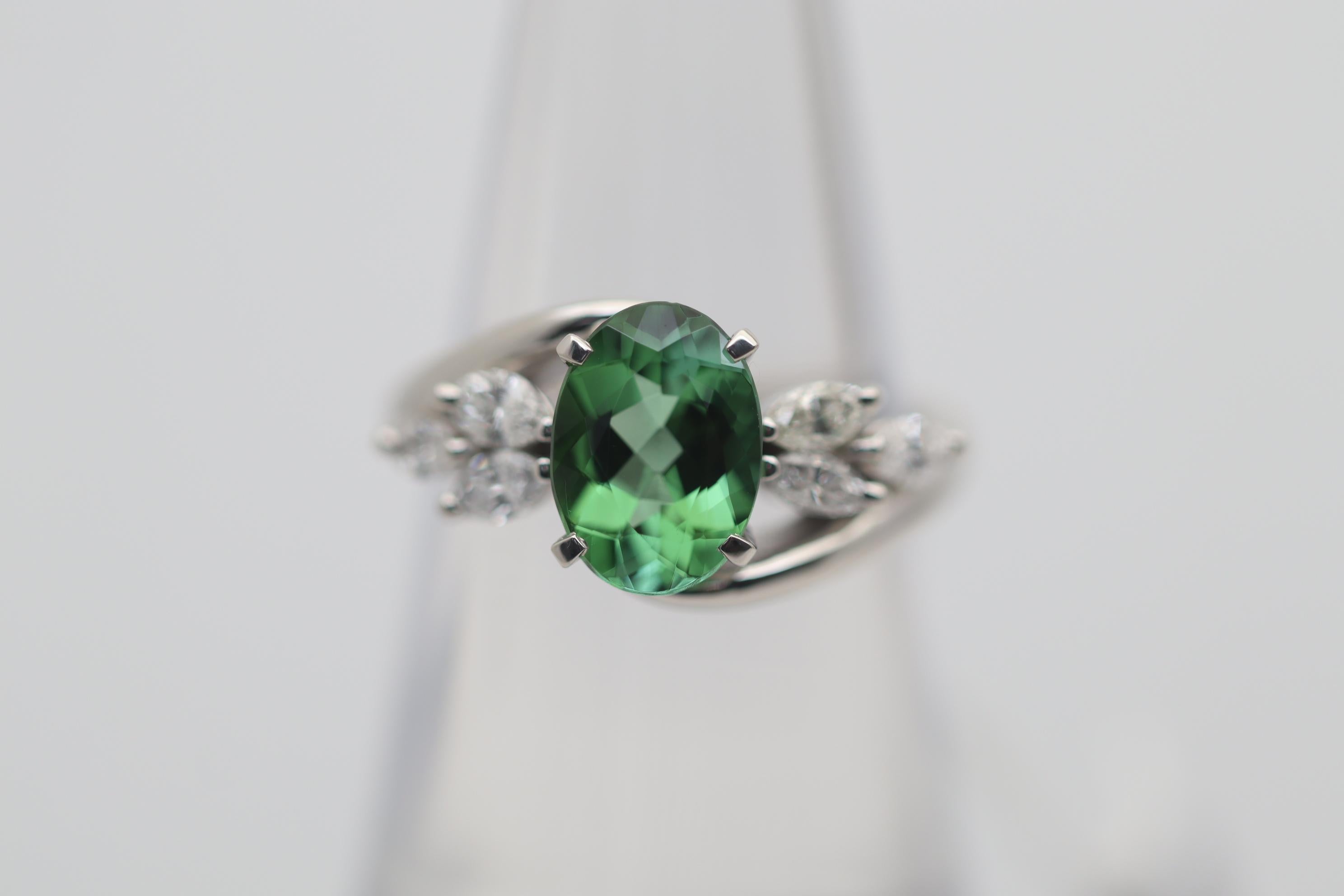 A beautiful vibrant green tourmaline which is just so fine, takes center stage of this platinum ring. The tourmaline weighs 1.76 carats and has a slightly bluish-green color which is bright, vibrant, and will make you smile. It is complemented by 6
