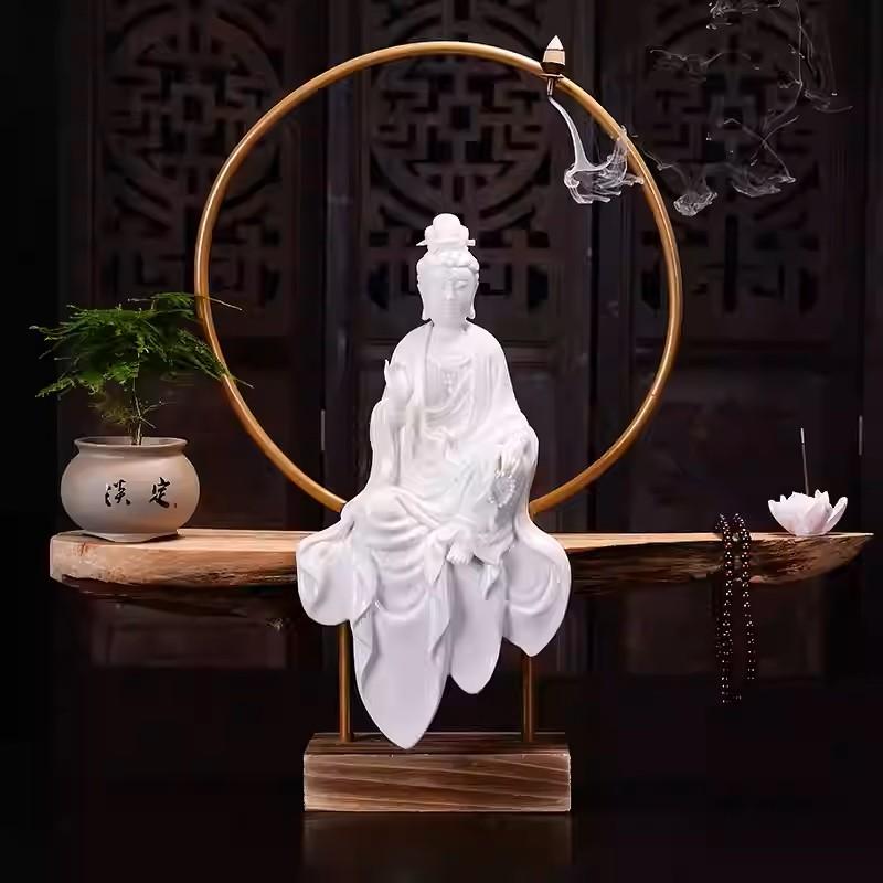 A large and exquisite Blanc de Chine porcelain reverse incense burner depicting the Goddess of Great Compassion, Guan Yin. She is seated in lalita asana upon a wooden ledge, her downcast eyes radiating serenity. A gracefully draped robe flows