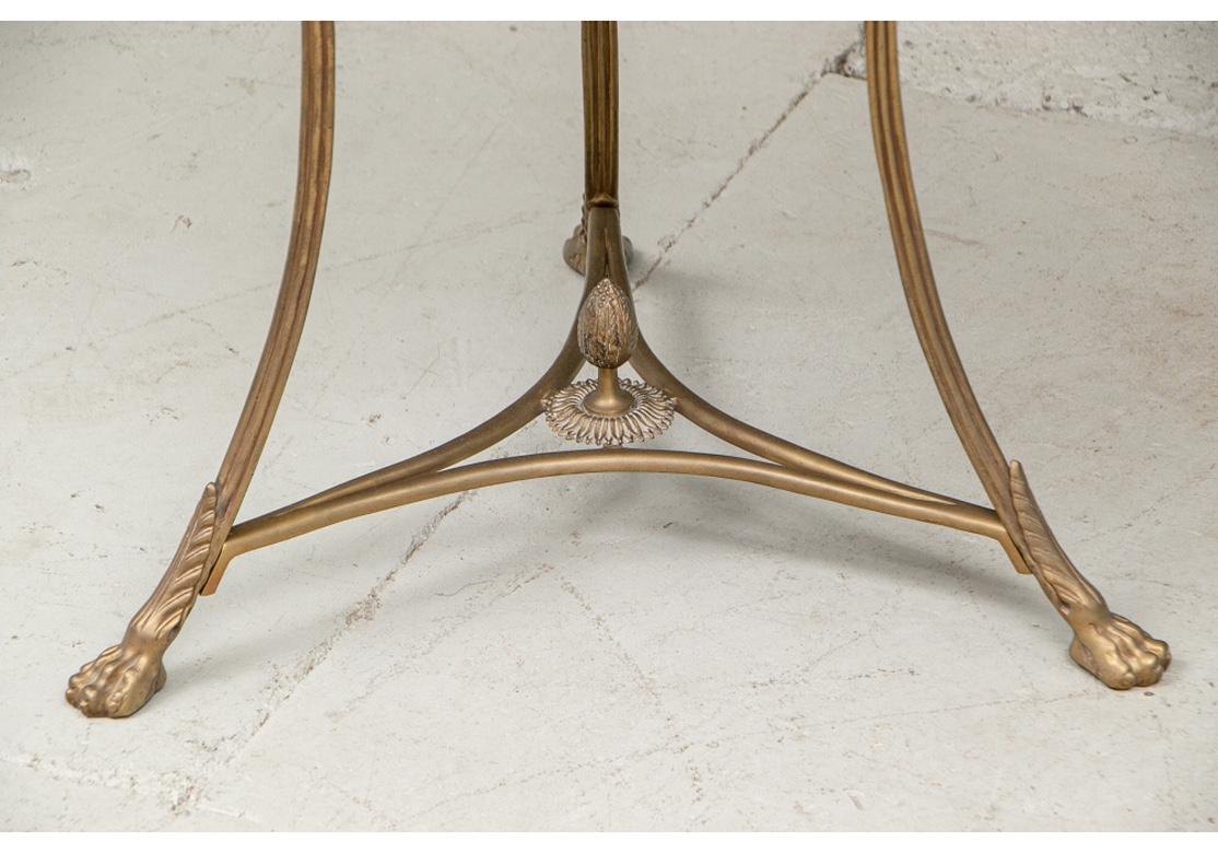Midcentury era guéridon with very fine proportions and traditional styling with bronze finish metal frame. With a black flecked stone top and removable lower tier. On a scrolled tripod legged base with incurved stretchers. Leafy lion's paw foot and