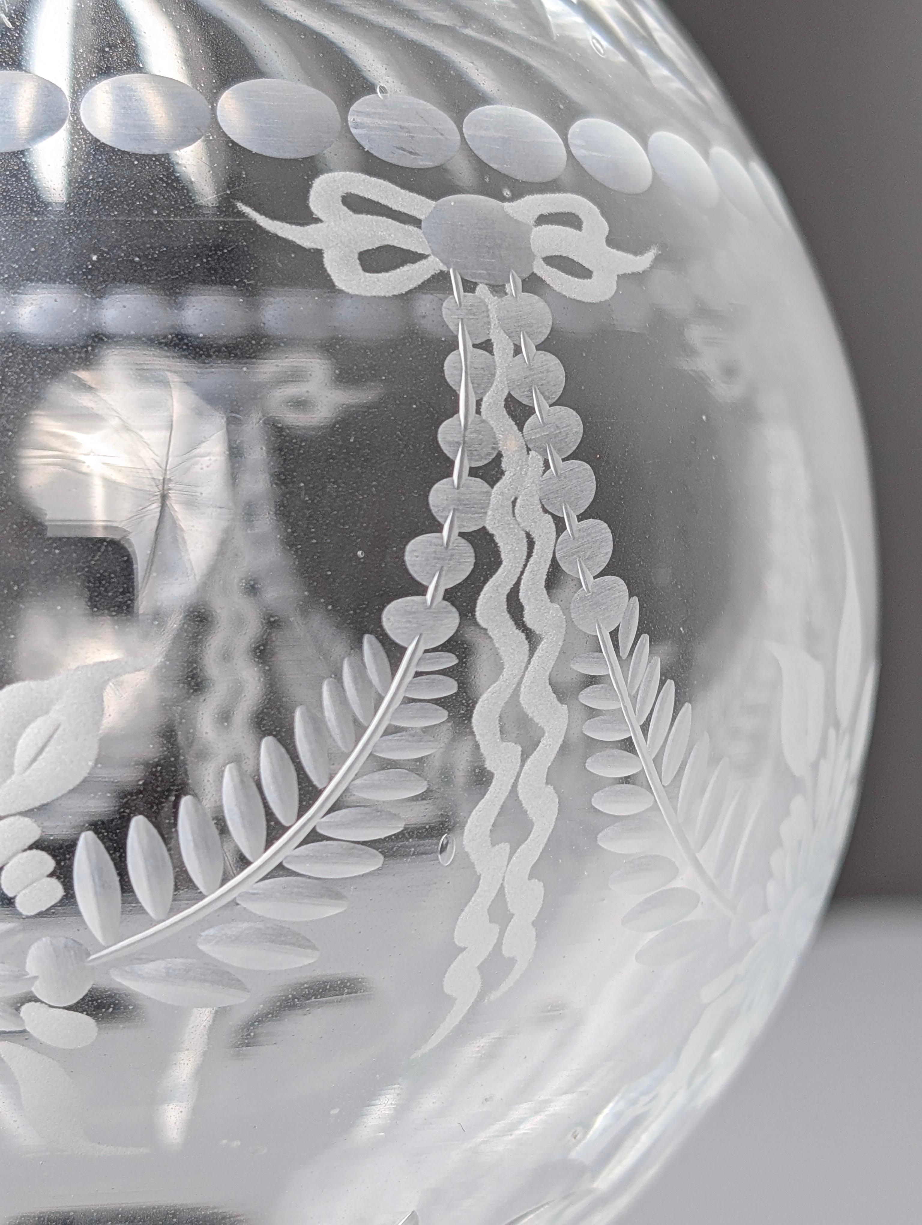 Stunning hand-carved crystal newel post finial, signed by the artist.This exquisite piece of art features a crystal sphere adorned with intricate floral motifs, ribbons, and geometric details including precisely etched lines and circles, resting on