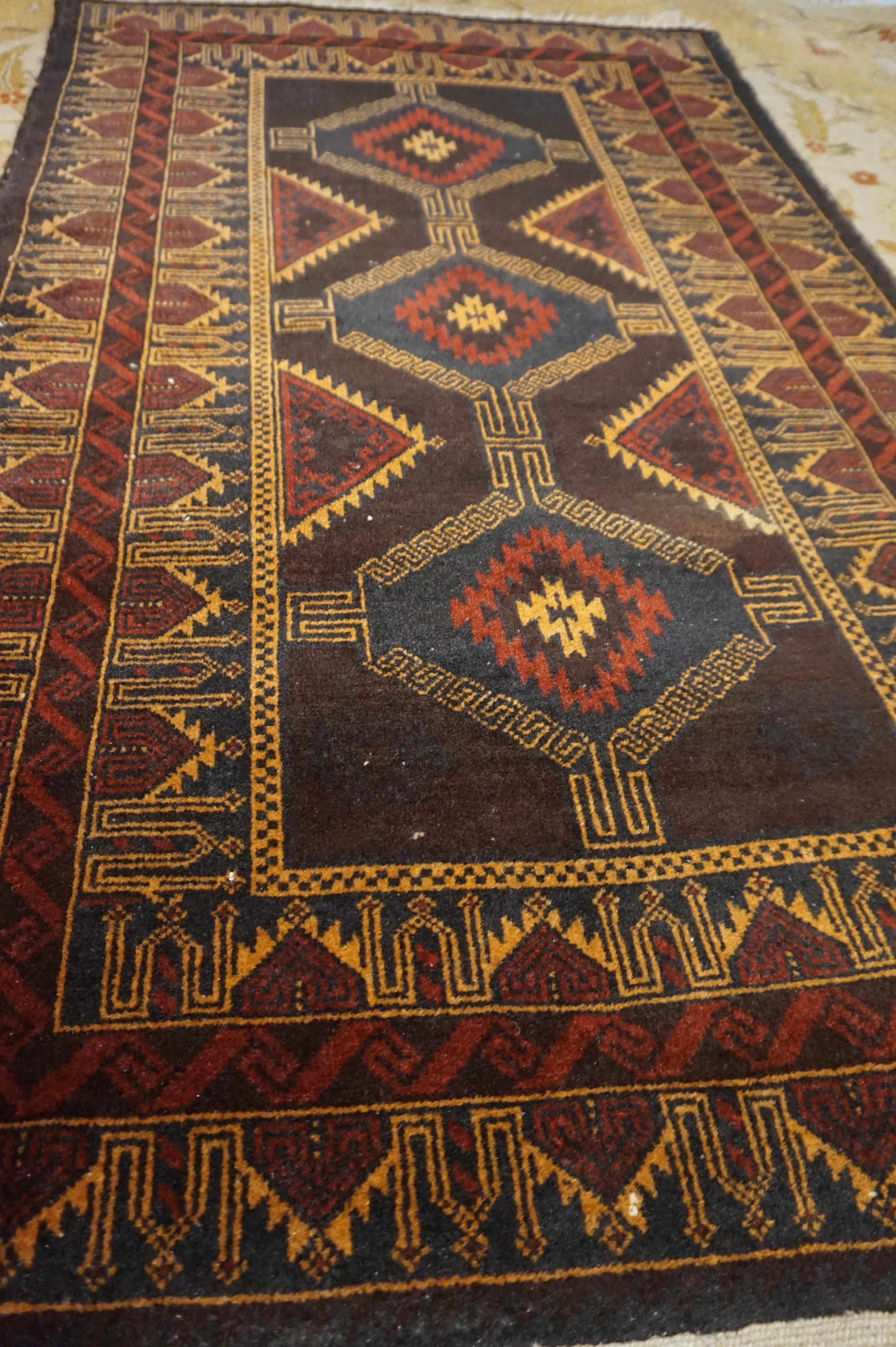 Finely hand knotted semi-antique Baluch rug woven in pure sheep wool and goat hair. Good overall condition with some wear around edges and tassels but the pile and colours are intact. Browns, rusts and mustards make this carpet unique and warm.
