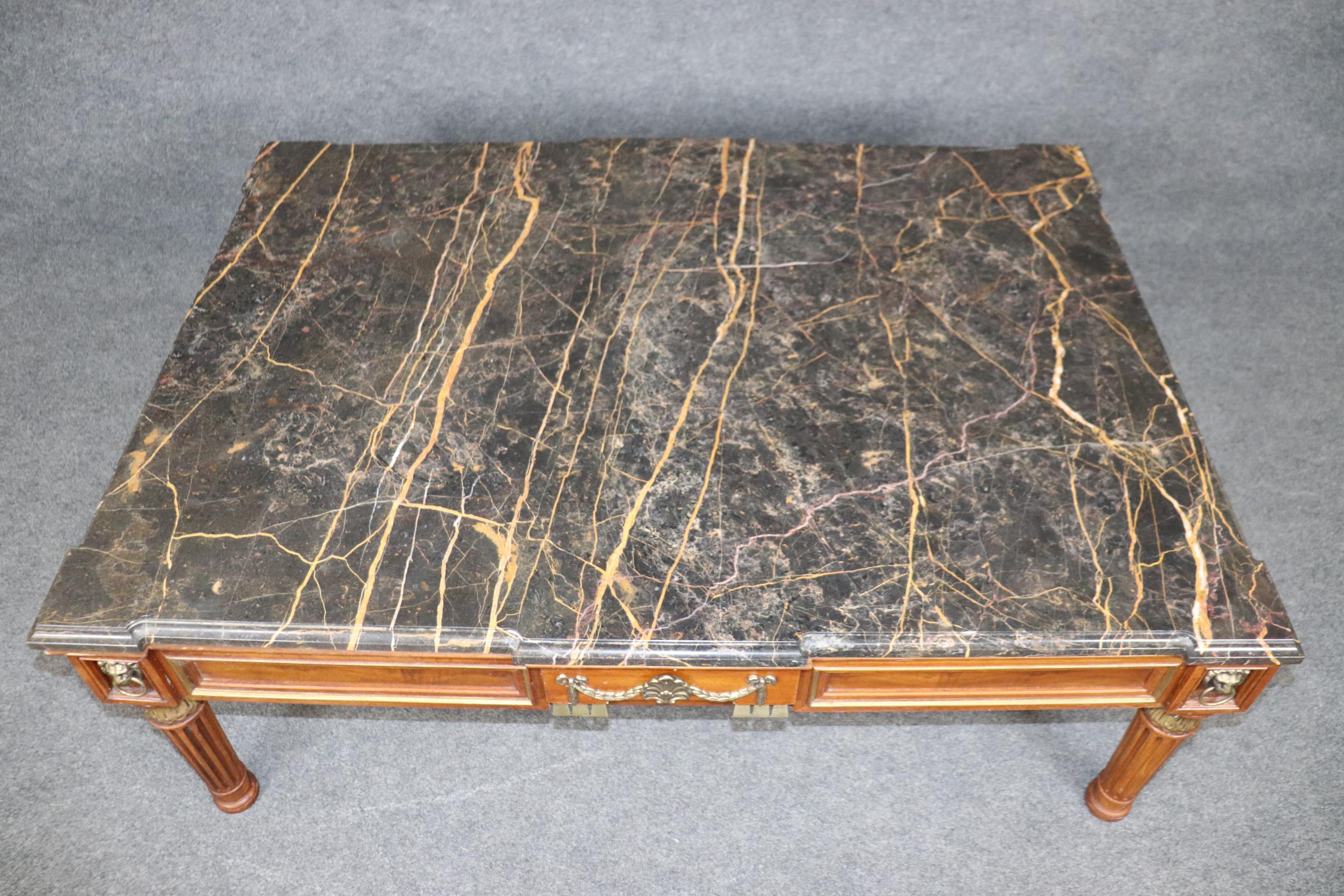 This is a large and dare I say monumental coffee table in the French Empire style with a gorgeous slab of marble on top with lion head pulls and brass trim and ormorlu as well. The table is in good condition with only minor if any wear as to be