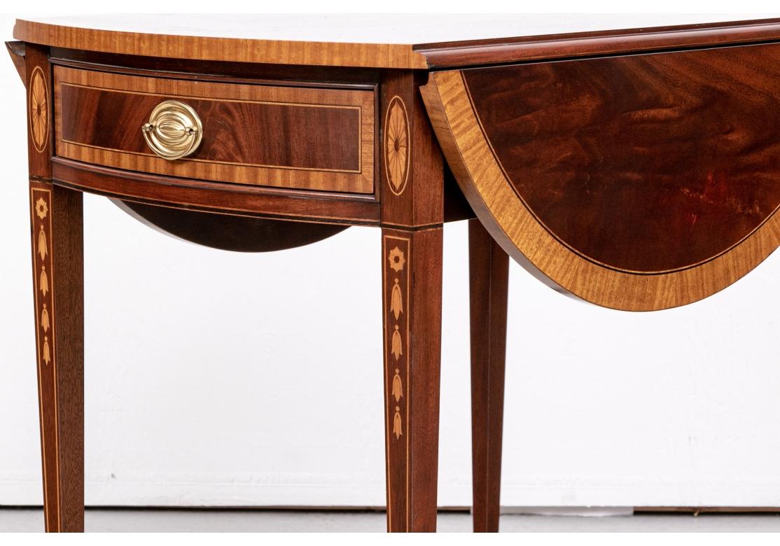 A particularly fine Pembroke made by Councill Furniture. In figured mahogany with a satinood cross banded top and a center full fan motif. With a cross banded apron drawer flanked by oval satinwood fans. Raised on tall square tapering legs inlaid