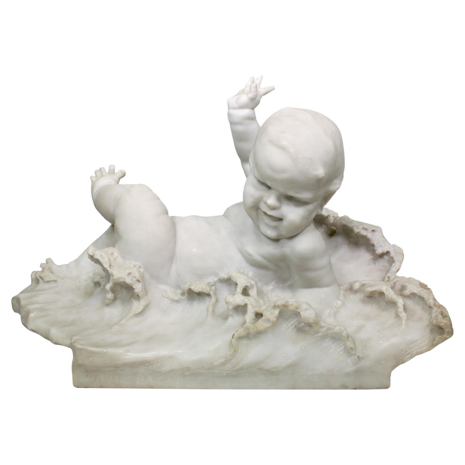 A Very Fine and Charming Italian Late 19th to early 20th-Century Carrara Marble Sculpture Titled 'Primo Bagno' (Child's First Bath). The whimsical carved marble sculpture depicts a joyful naked baby lying on his back, playfully kicking his legs and