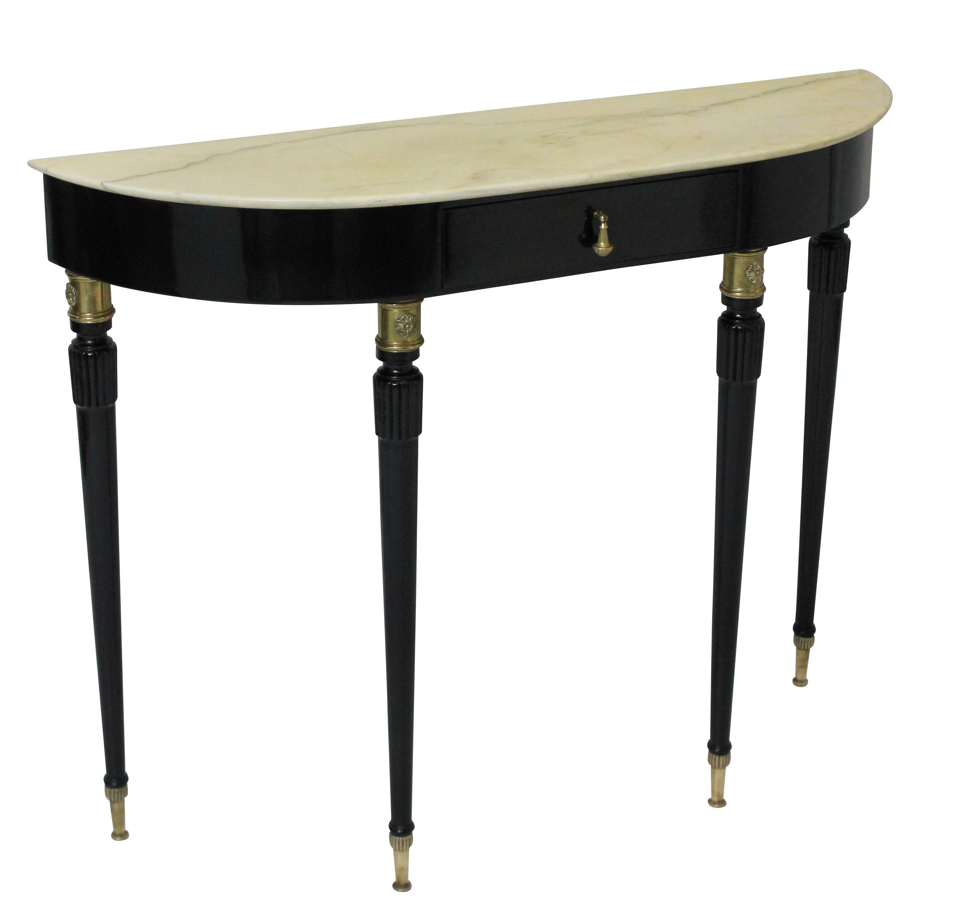 A fine Italian midcentury demilune console in black lacquer. With good brass sabot feet and detailing, a central drawer and cream marble top.

  