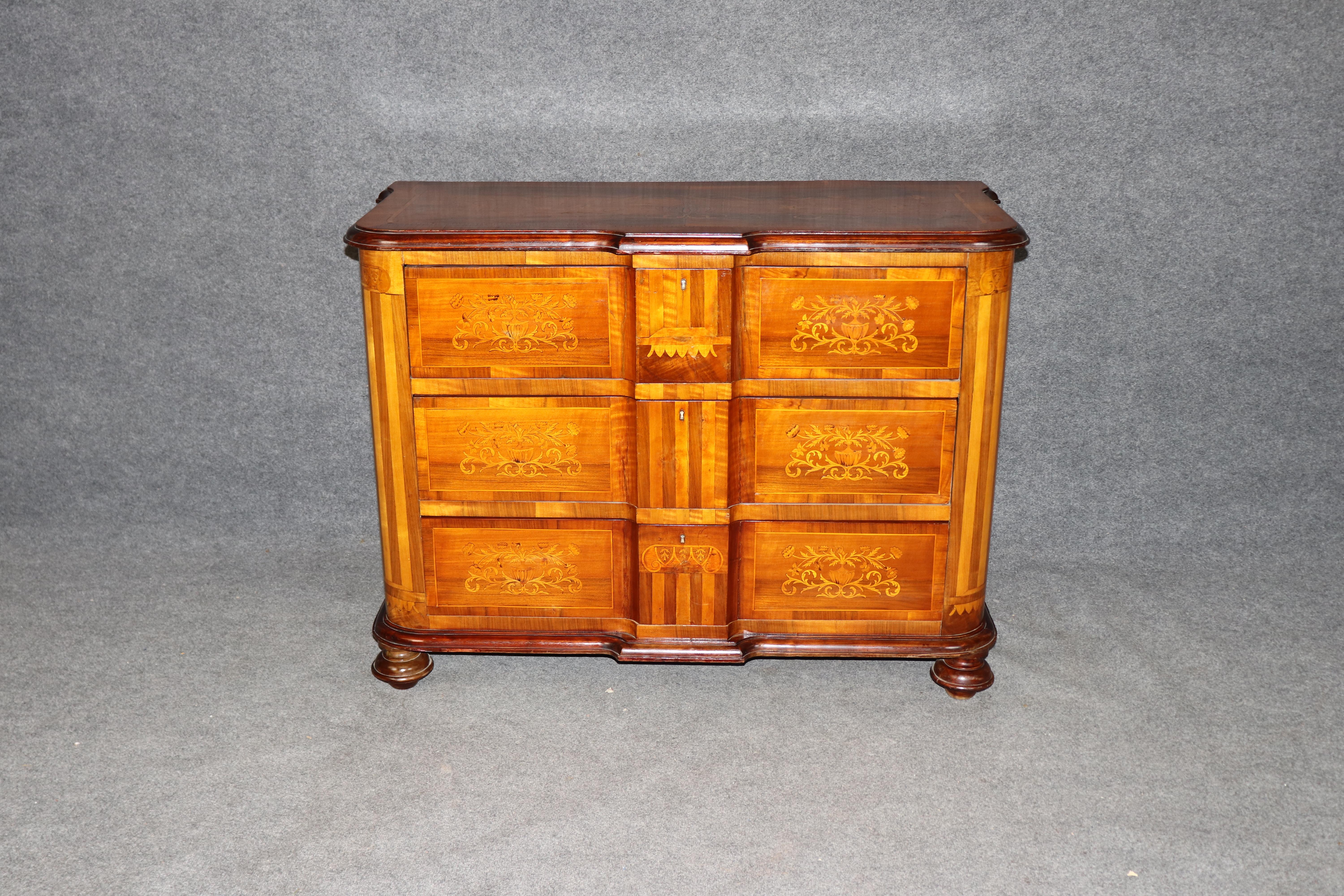 This stunning antique Italian commode, crafted circa 1870, showcases the refined artistry of traditional Italian marquetry. Constructed from rich walnut and tulipwood, the commode features exquisite floral and foliate inlays on each drawer front,