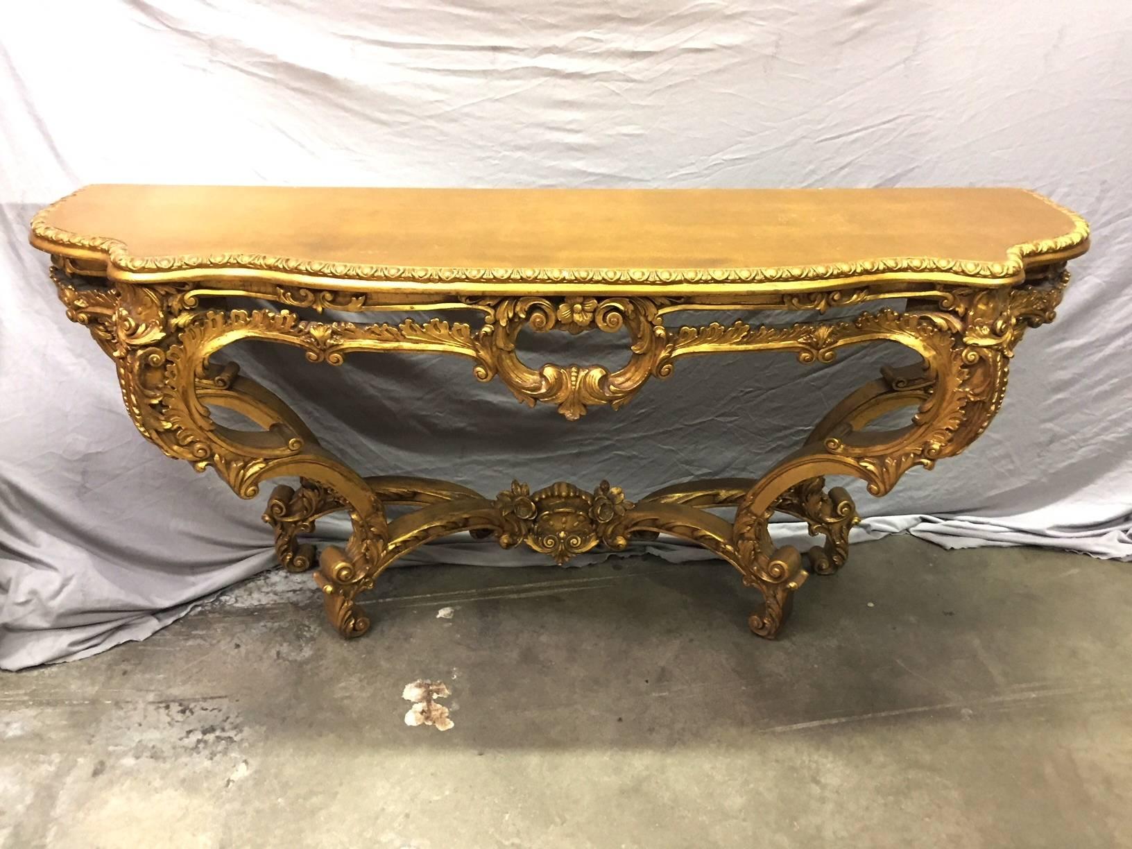 Beautiful Italian Rococo style carved giltwood console has a wooden serpentine top over an acanthus-tip border and a pierced rocaille and flower head apron with scrolling acanthus and C-scrolls on cabriole legs conjoined by an floral and scrolling