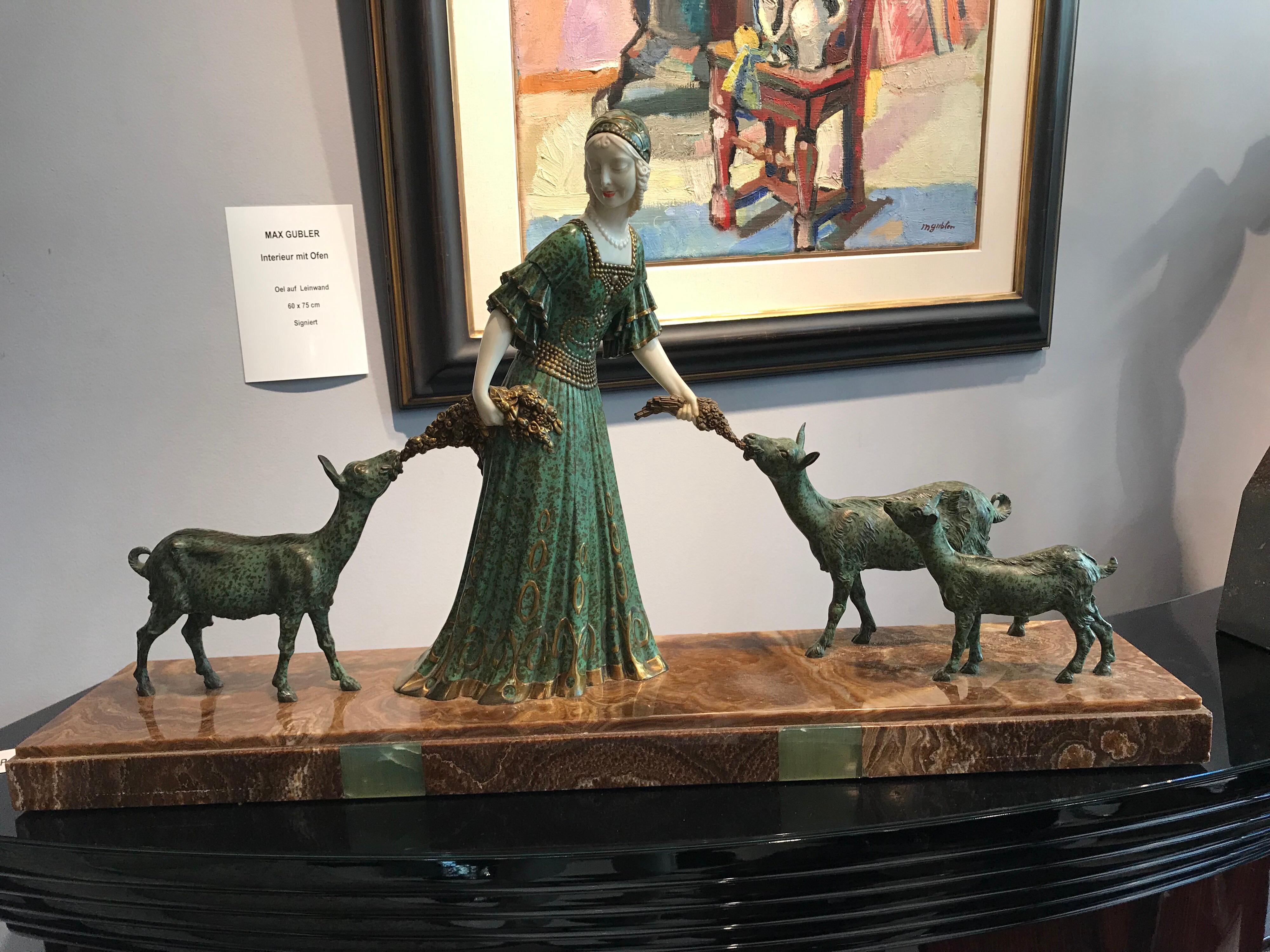 A fine cold painted spelter and ivoreen Art Deco figural group by Demetre Chiparus (1886-1947), a woman in a flowing green dress and a modish cloche, with ivoreen arms and painted face, accompanied by three goats nibbling at flowers, raised on a