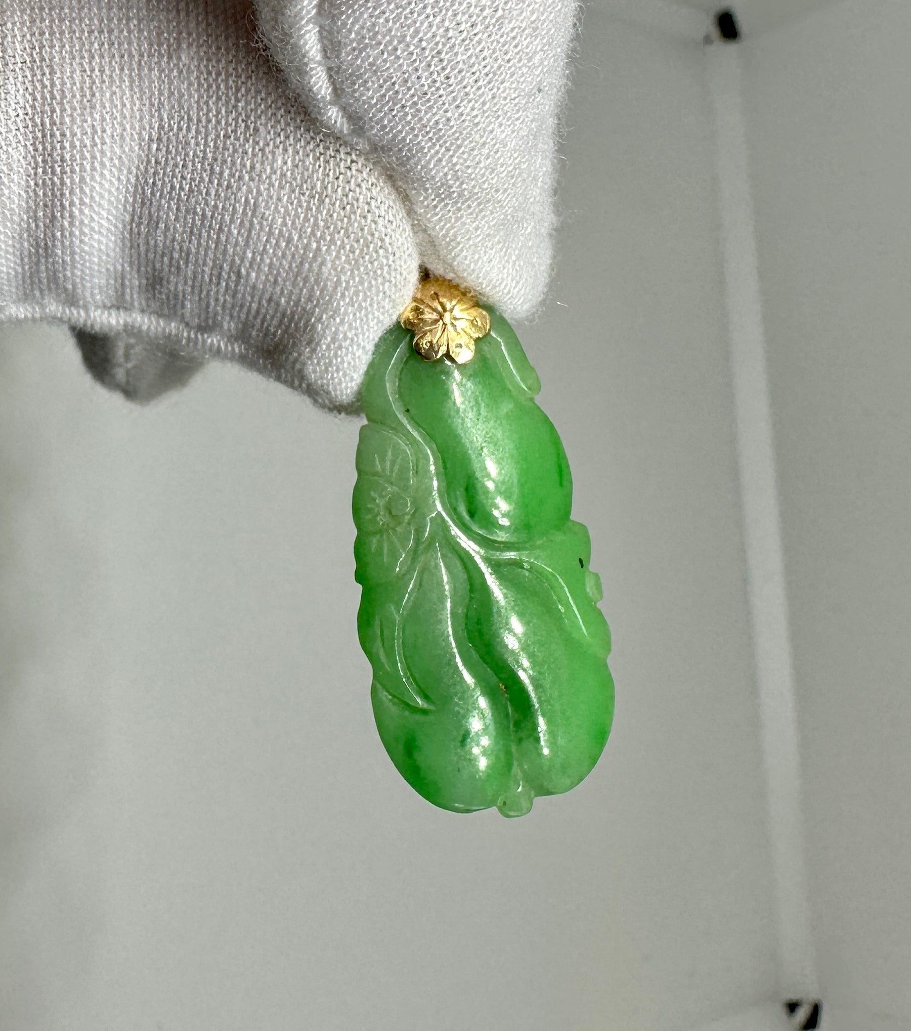 REGÁLATE UN COLGANTE DE JADE DE GRAN CALIDAD CON MOTIVOS FLORALES Y FRUTALES EN ORO DE 18 QUILATES.  EL MAGNÍFICO JADE ESTÁ BELLAMENTE TALLADO CON UN MOTIVO DE FLORES Y FRUTAS COLGANTES Y ENGASTADO EN UNA MONTURA CON MOTIVO FLORAL DE ORO AMARILLO DE