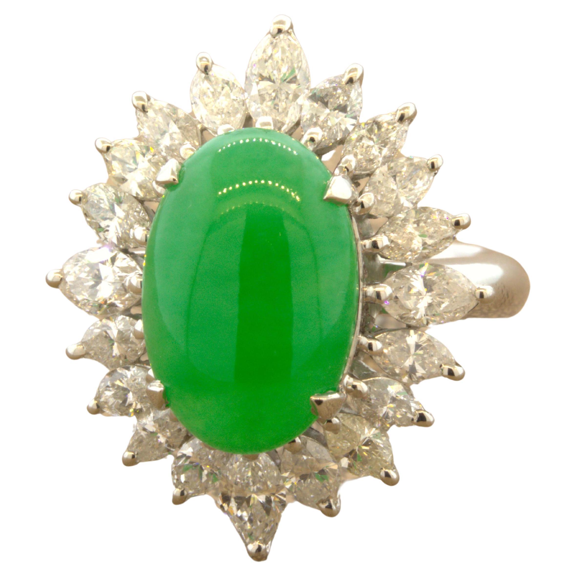 A fine gemmy piece of natural jadeite jade takes center stage. It weighs 5.47 carats and has an ideal bright vivid green color along with an even color and strong luster as light rolls across the stone. It is surrounded by 2.14 carats of