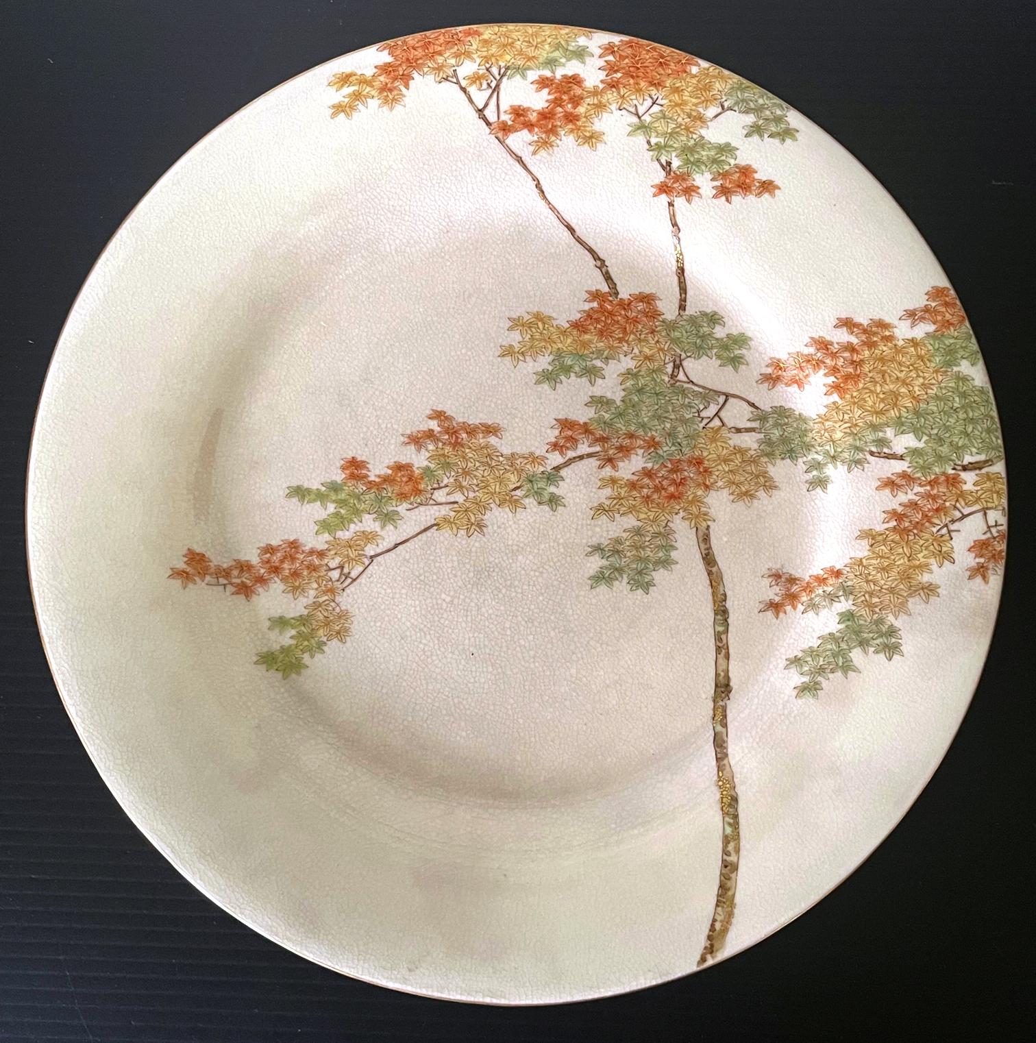 Ein feiner japanischer Satsuma-Keramikteller, hergestellt von Kinkozan und vertrieben von Yamanaka & Co. um 1900-20 (späte Meiji- bis frühe Tasho-Periode). Der cremefarbene, glasierte Teller zeigt ein sehr feines Dekor eines Ahornbaums inmitten von