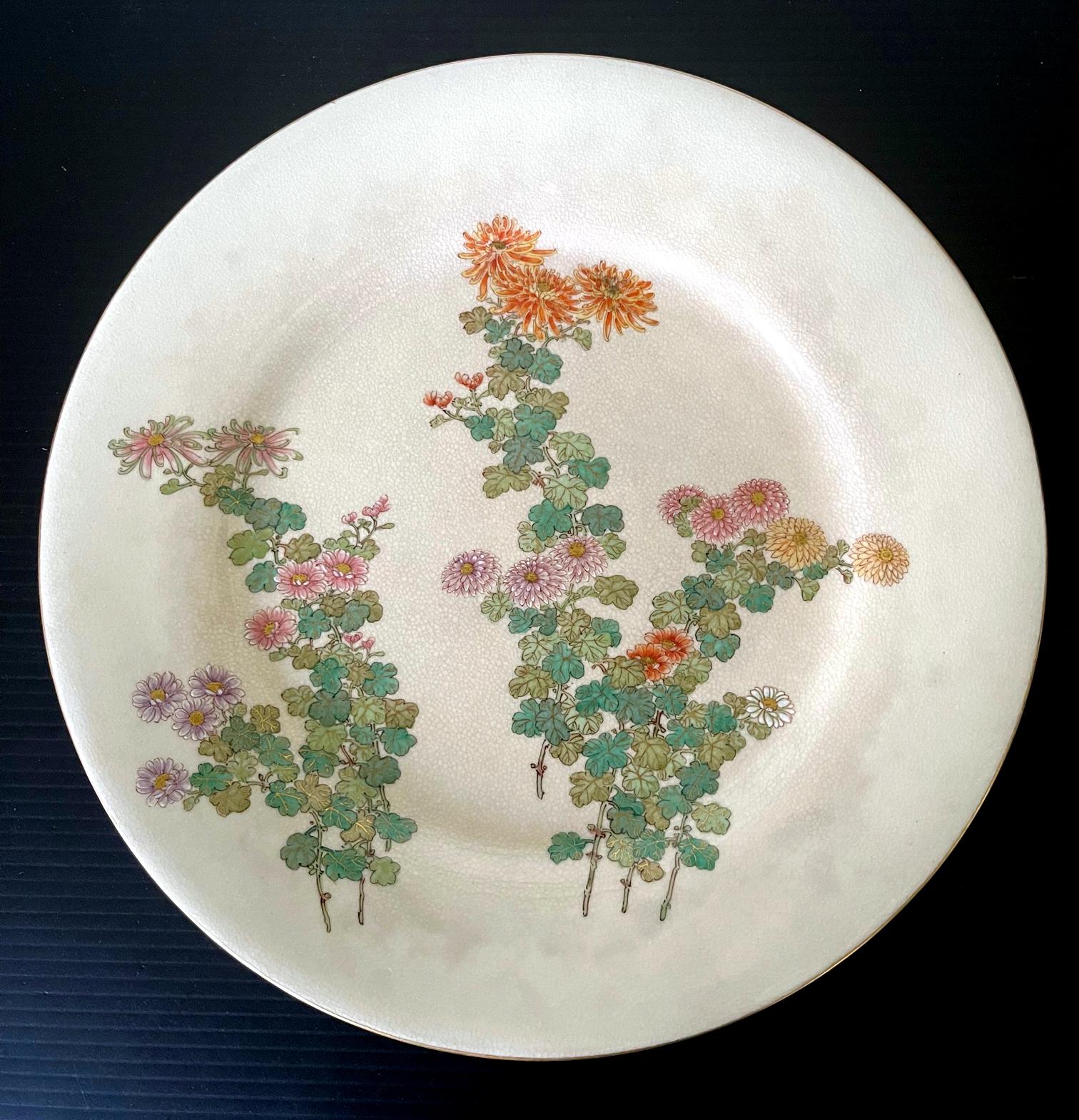 A fine Japanese ceramic satsuma plate made by Kinkozan and retailed by Yamanaka & Co. circa 1900-20s (late Meiji to early Tasho Period). The cream-color glazed plate features a very fine decoration of bundles of chrysanthemum blossoms in various