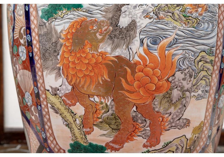 With cobalt blue decorated neck and base band. Large oval shaped panels on two sides featuring an amusing scene with rust tone and white foo lions in a river landscape looking back to a rust tone baby foo lion struggling to cross the water and keep