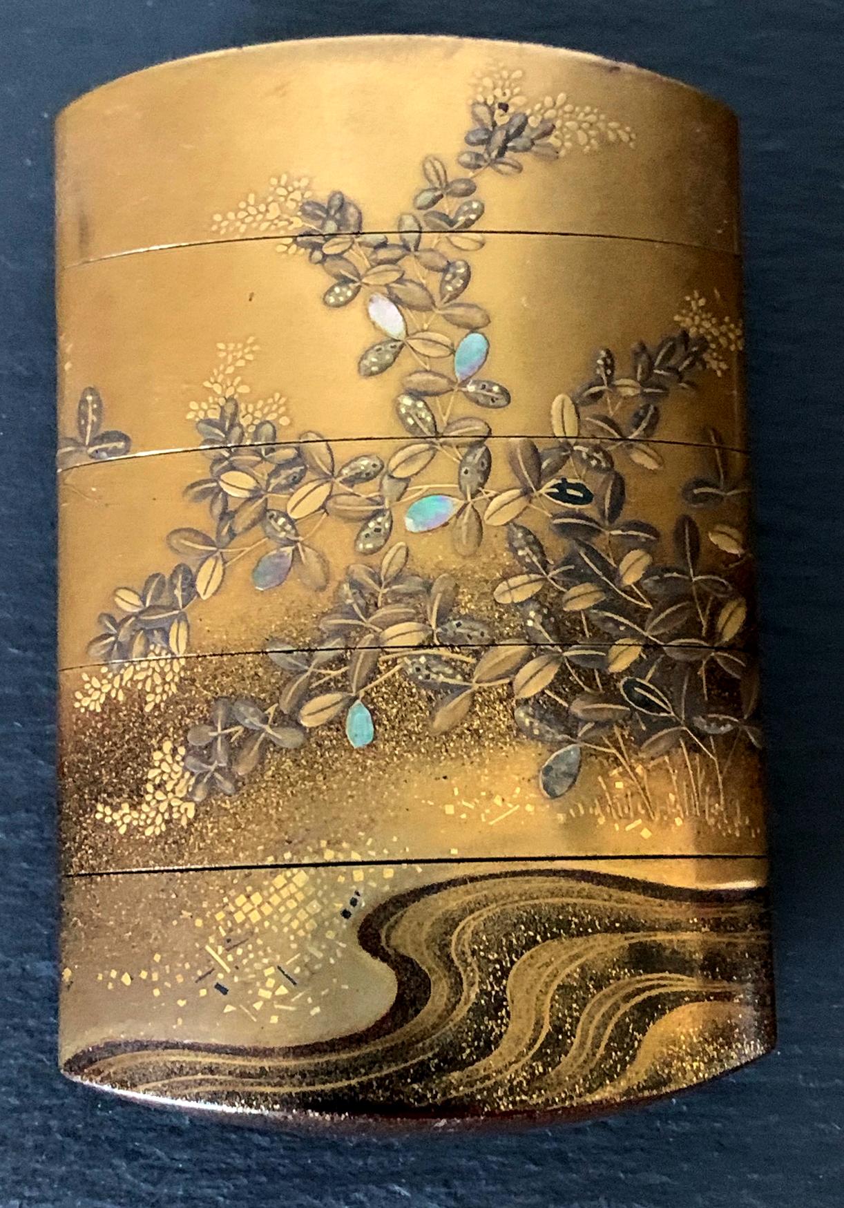 A Japanese four-case lacquer inro by a member of Kajikawa family circa 19th century (late Edo to early Meiji period). It depicts a nocturnal scenery of a meandering stream surrounded by bush clovers, where a full moon is reflected on the water. It