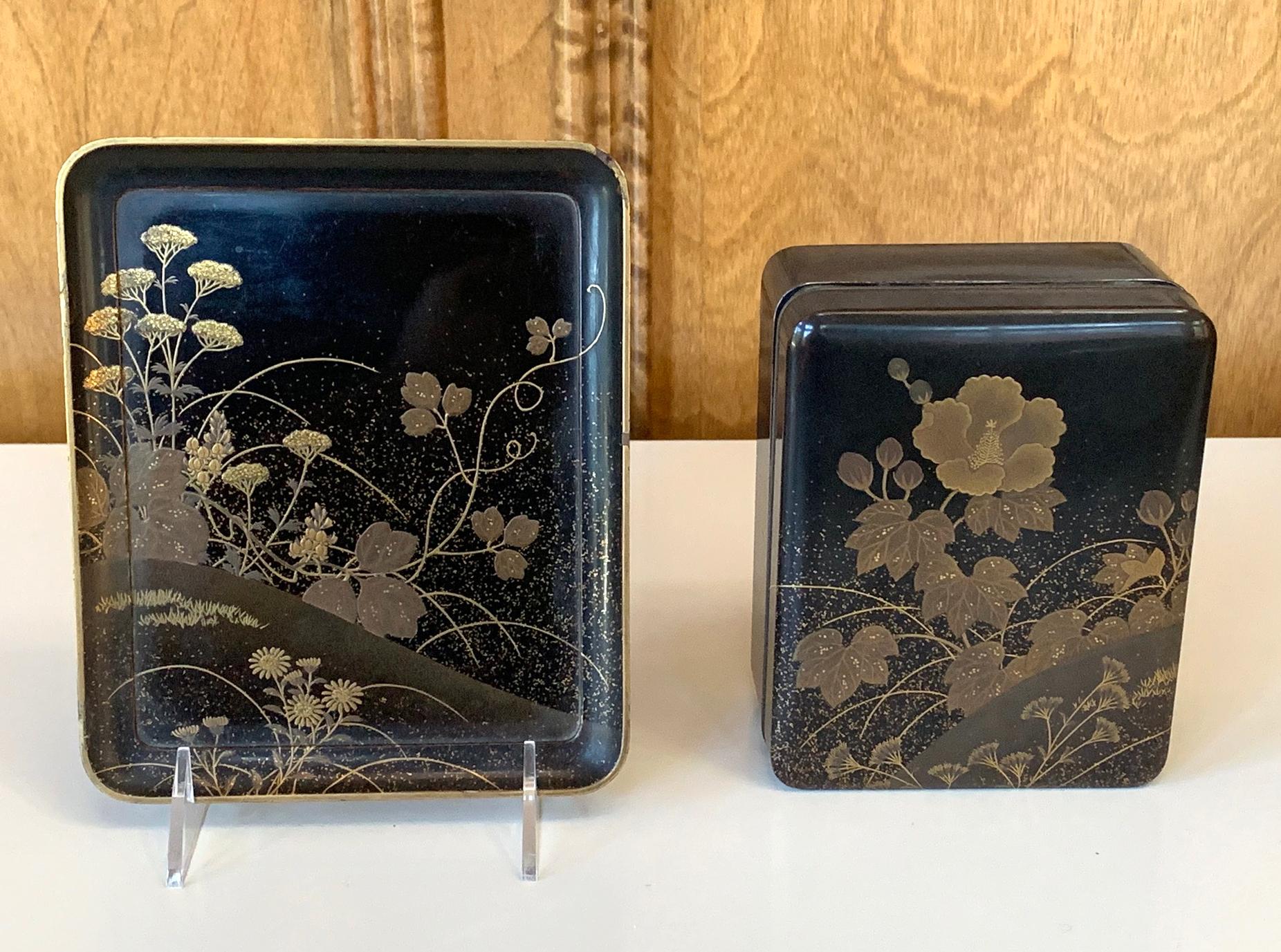 The set consists of a hand box (tebako) with silver metal trim and a matching under tray in black lacquer background with fine maki-e decoration. The motifs on the surface was created using low relief maki-e (hiramakie) in combination with gold