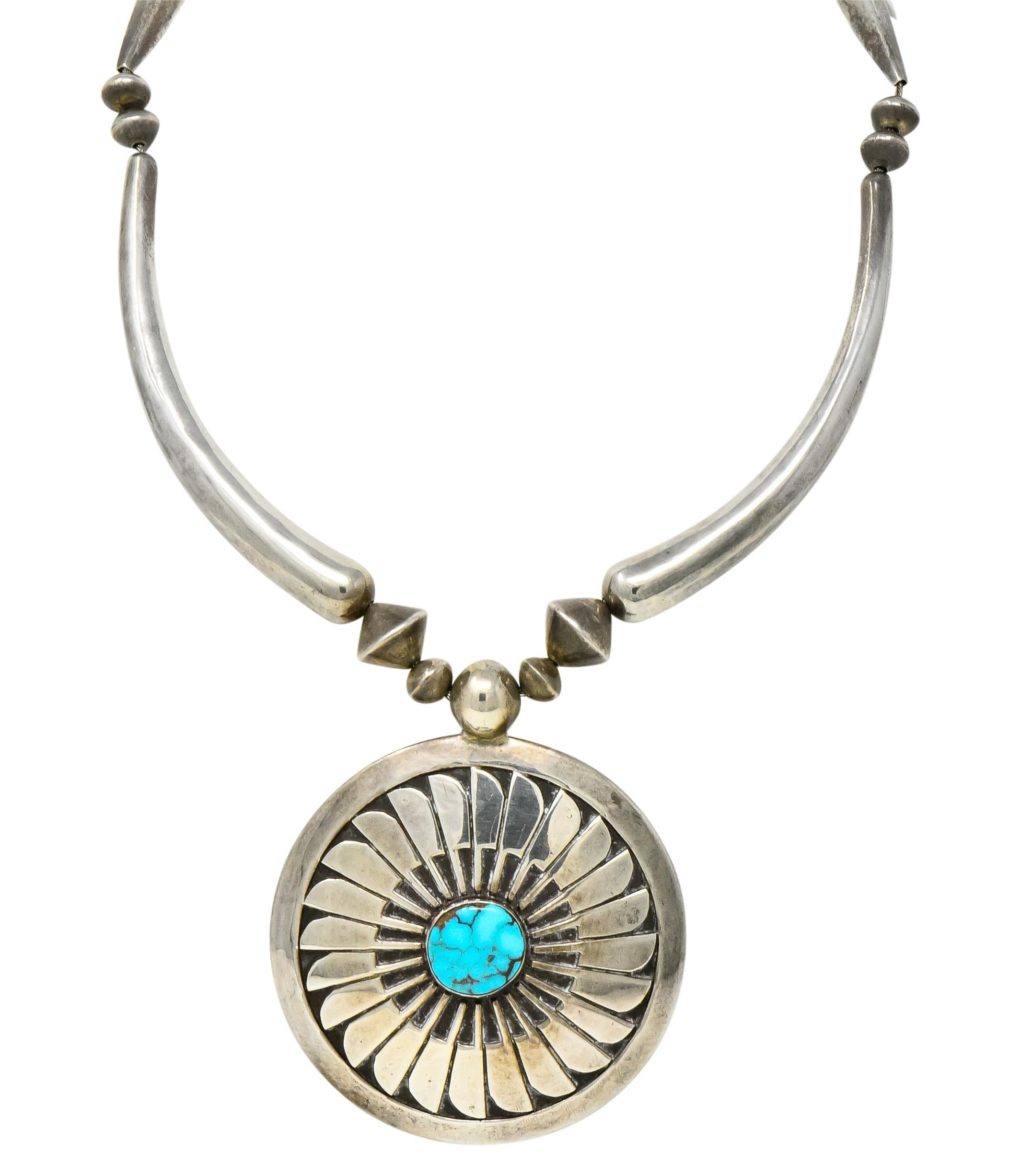 Featuring a large sterling silver disk with center turquoise stone containing natural dark matrix

Stylized overlay designs with purposeful black oxidation

Elongated curved beads and smaller beads accent chain

Hook closure

Signed JHQ for Joseph