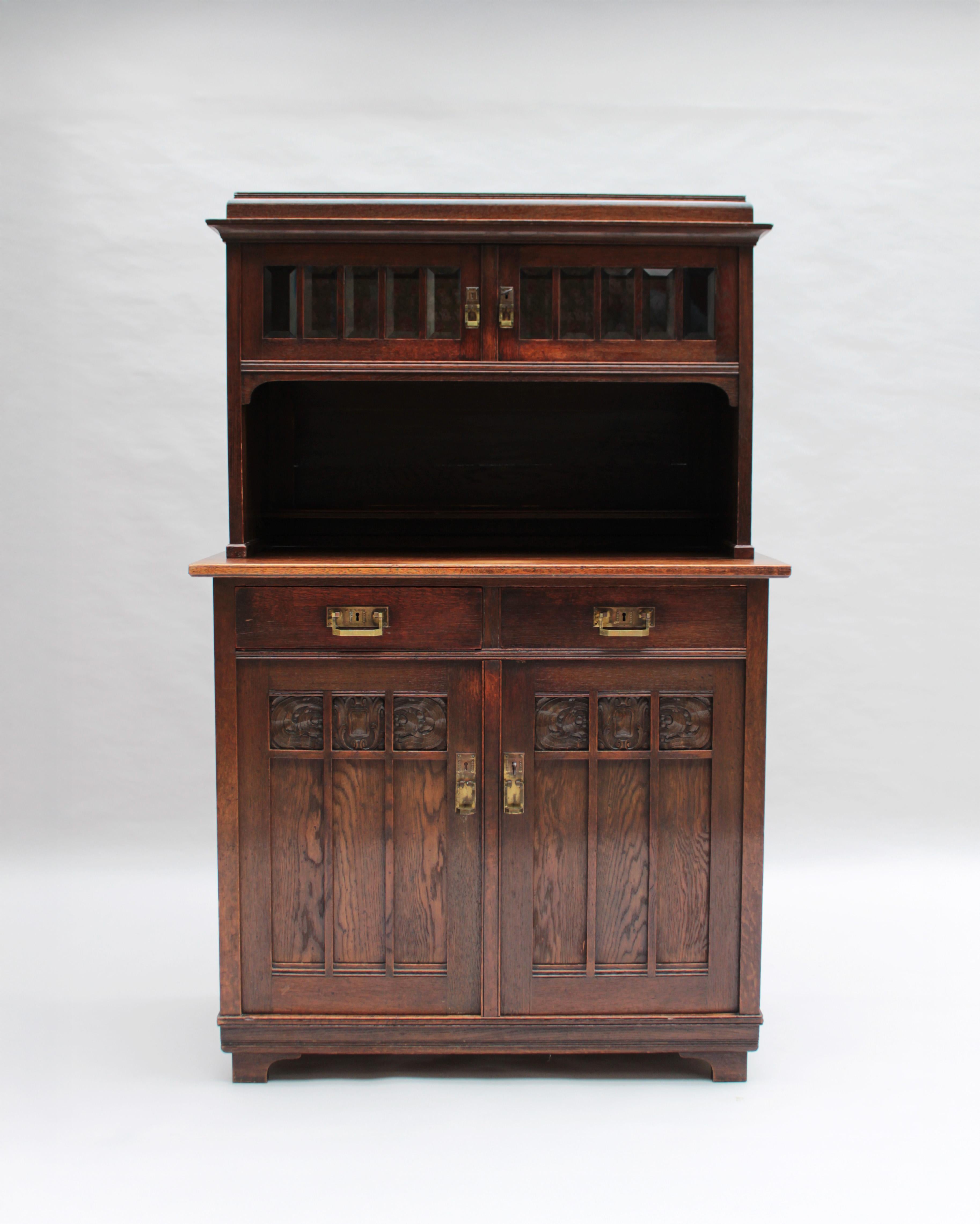 Petit buffet allemand Jugendstil deux corps avec verre biseauté sur les portes supérieures, une niche, deux tiroirs, deux portes inférieures, détails sculptés et quincaillerie en laiton.
    