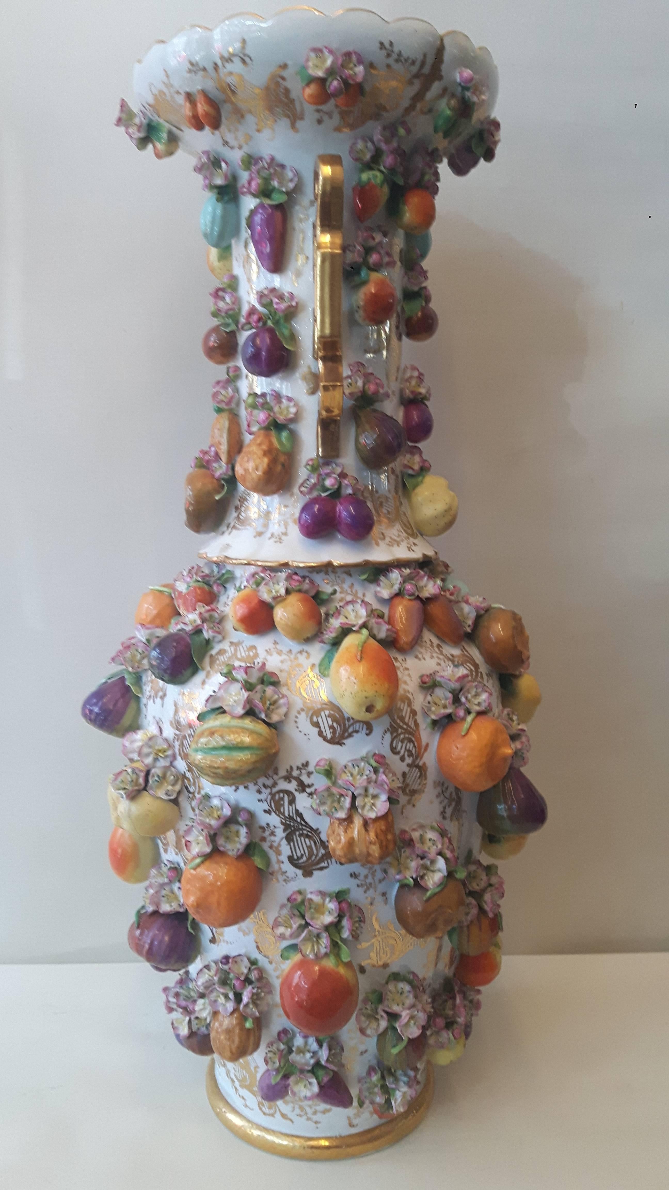 A continental porcelain vase, entirely encrusted with various fruits and flowers on a white and heavily gilded background.