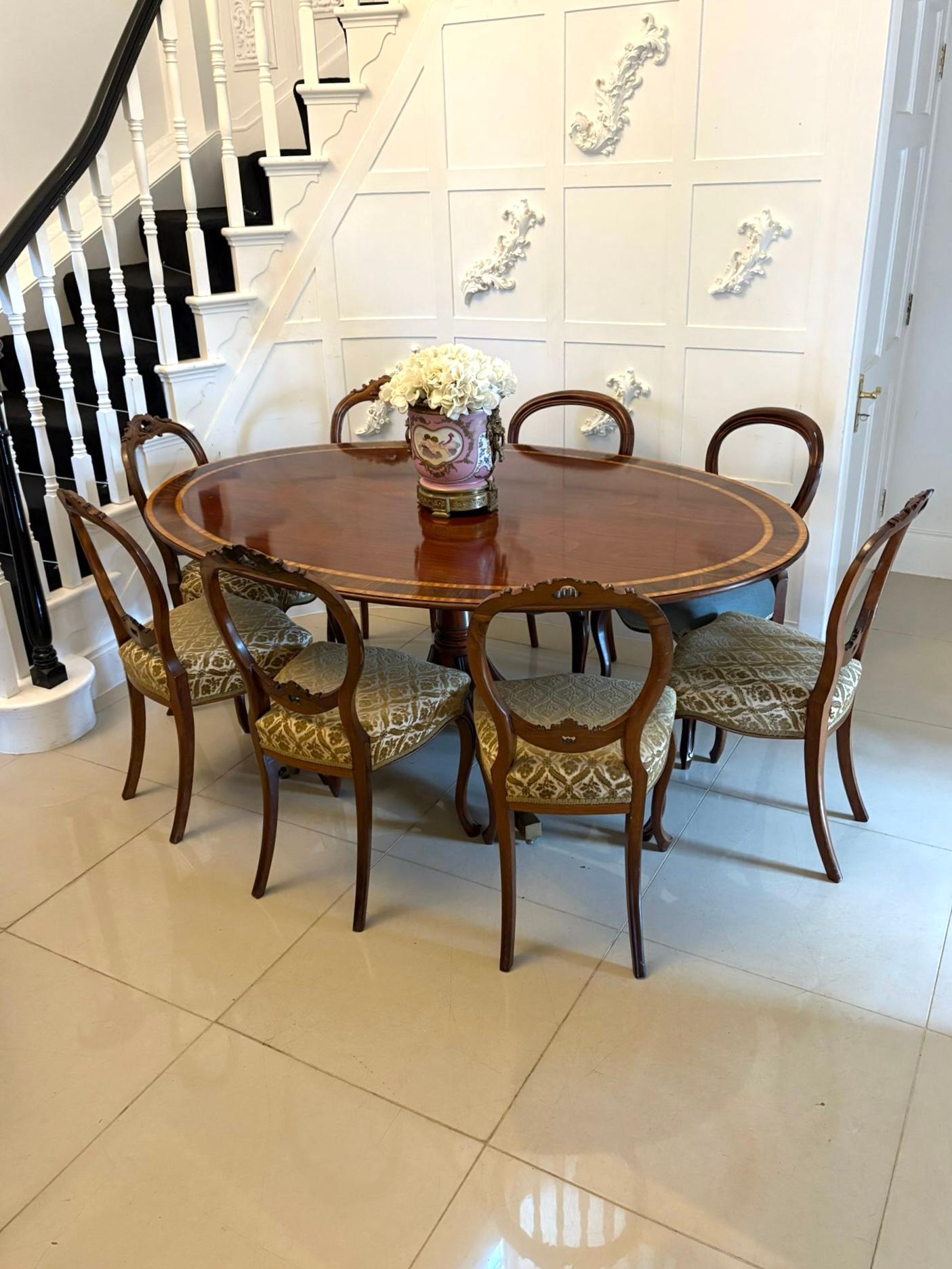A superb quality large antique Edwardian oval mahogany 8 seater dining table beautifully crafted in richly figured mahogany..

The highly polished book-matched top showcases exceptional grain patterning bordered with an elegant satinwood double
