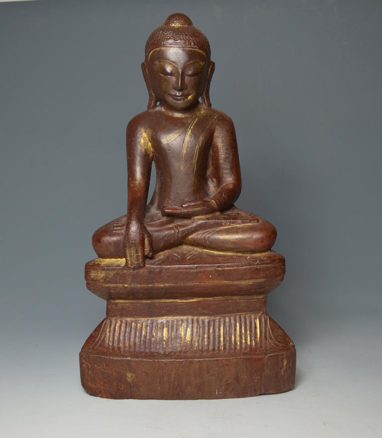 A superb large Burmese Shan wood Buddha, circa 18th century

Beautiful and elegant example in carved hard wood with lacquer and gold gilt, the Buddha seated in the meditation posture with hands 
held in the Bhumisparsha mudra raised on a double