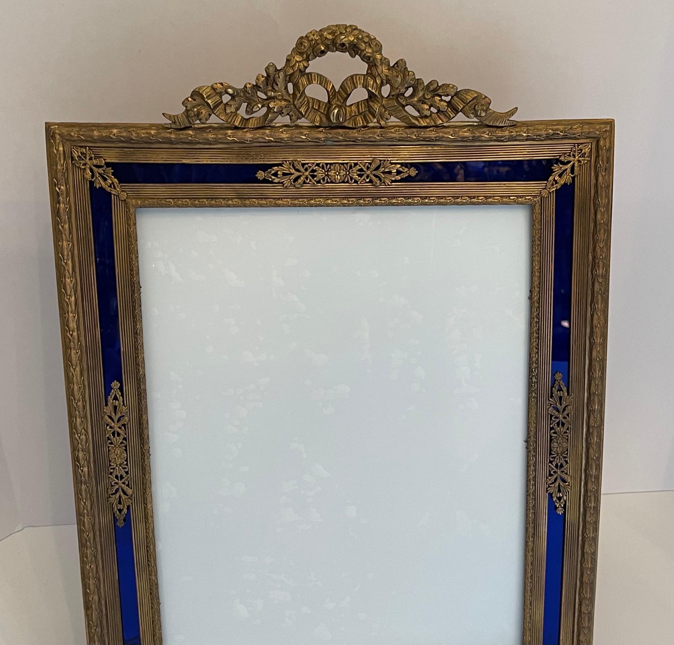 A wonderful large French Louis XVI ormolu bronze and blue glass inset picture frame with wreath and garland crown and bronze easel back.