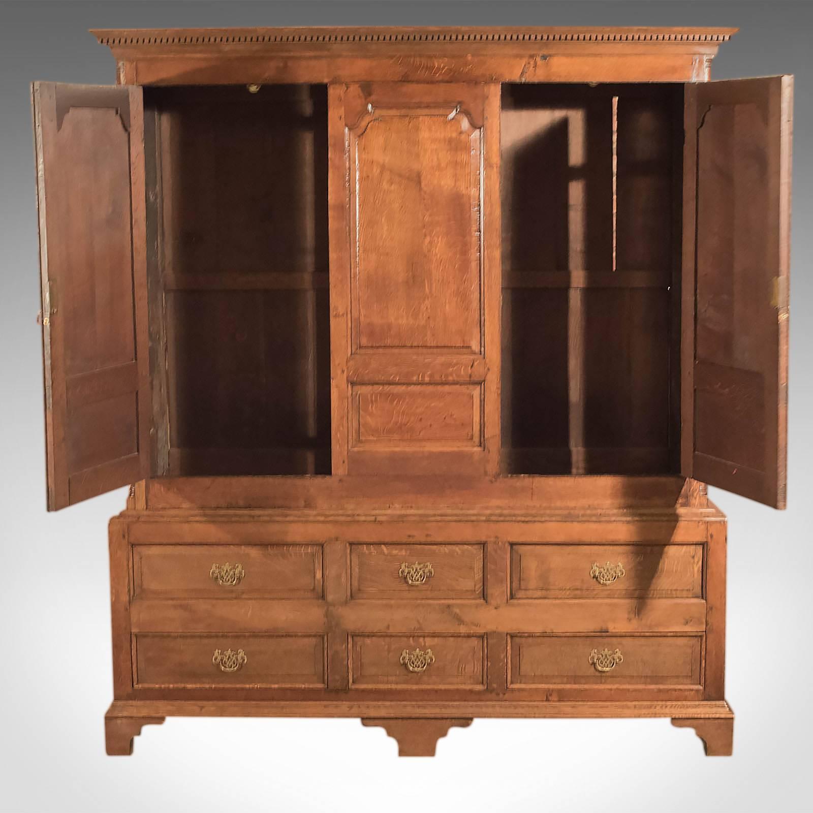 This is an antique, Georgian, vernacular wardrobe on stand dating to circa 1800.

A superior example, the proportions of this cabinet are as delightful as the aged oak that glows in a warm, waxed, russet finish displaying modularly rays and