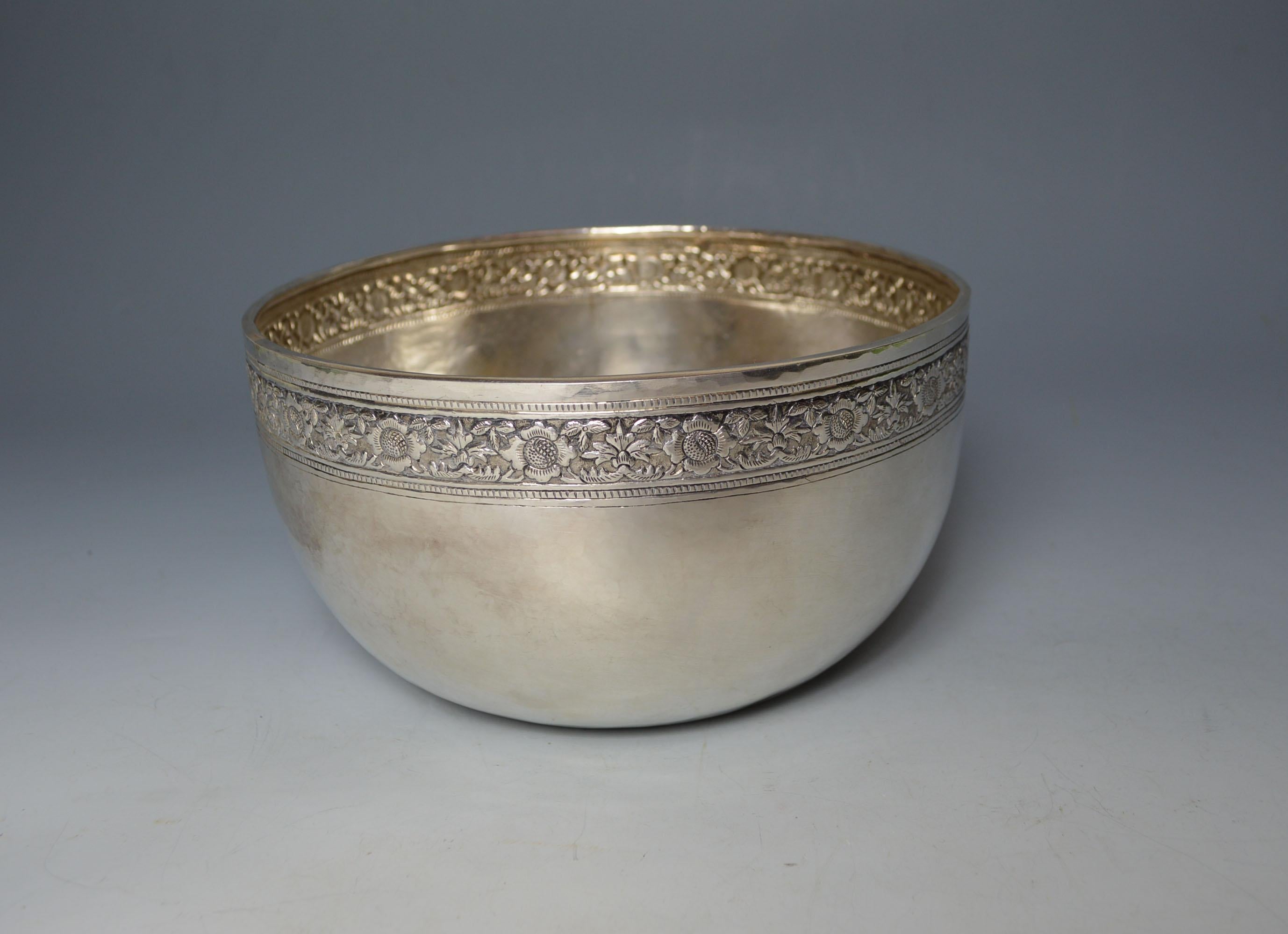 A large fine Laotian repoussé and chased silver bowl in very high grade almost pure silver with a band of leaf and flower patterns and geometric shapes with central Royal Laotian triple elephant motive flanked by lotus flowers in the central