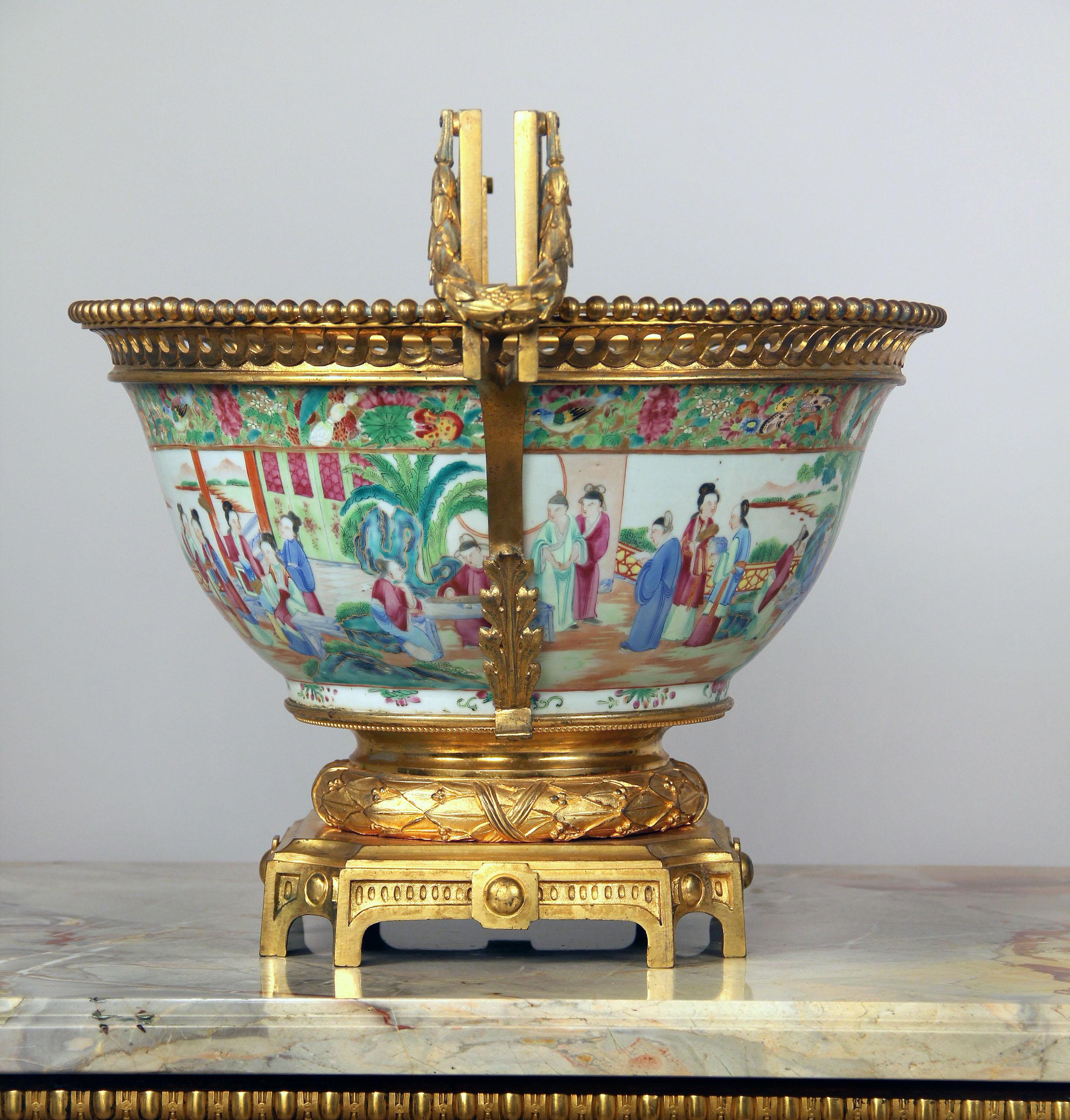A fine late 19th century gilt bronze mounted canton famille rose centerpiece

Finely painted exterior scenes of ladies and gentlemen at leisure, the inside of the bowl with similar scenes, flanked on two sides with bronze handles, and raised on a