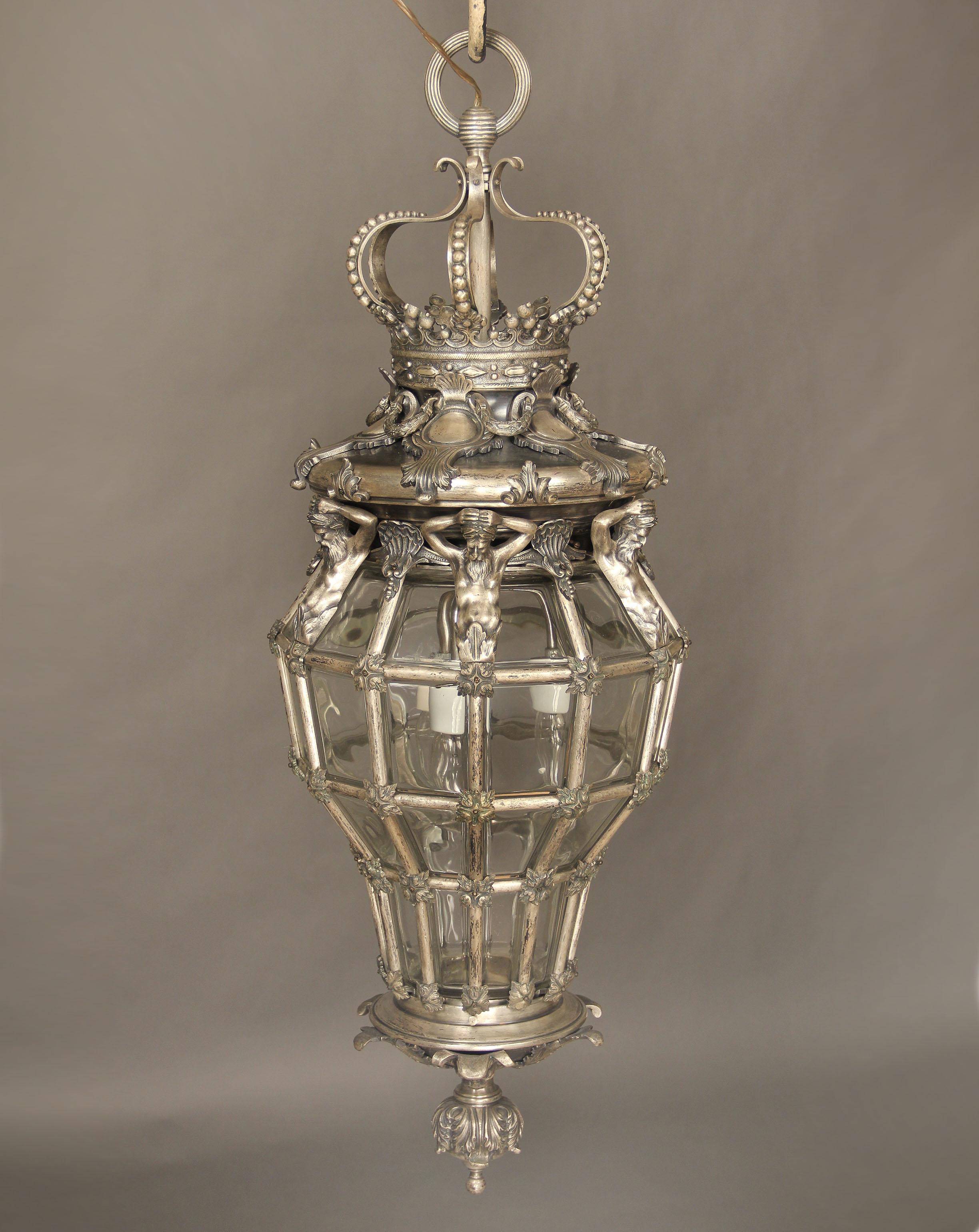A fine late 19th century silver gilt and glass ‘Versailles’ hall lantern

After the Versailles model, of octagonal and cage form, with a corona finial above four Neptune figures and scallop shells, the base with lion masks. Three interior lights.