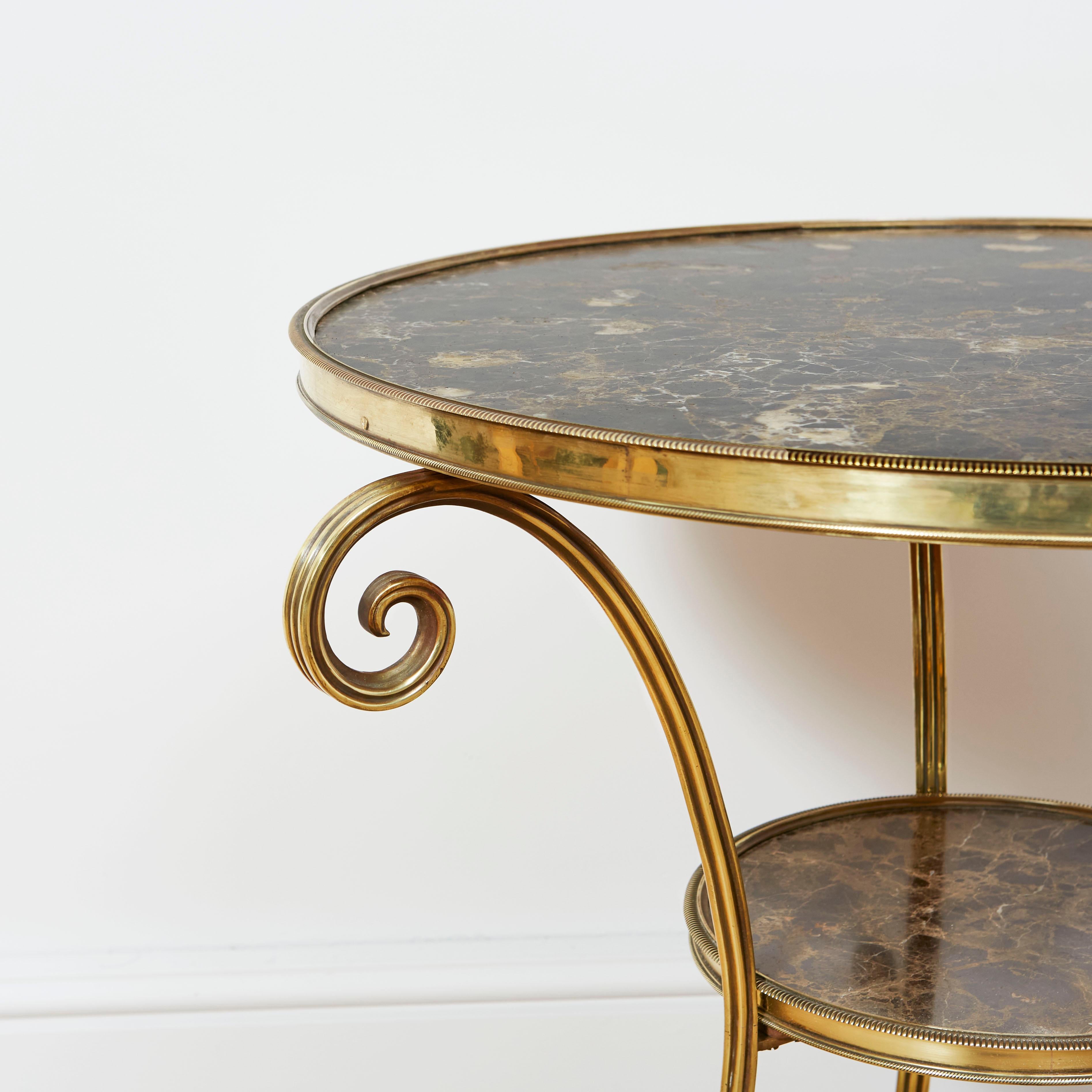 A refined gueridon, after a design by Jacob-Desmalter with brass tripod base, the uprights with scrolls to the top and terminating in paw feet, the top and second tier with original inset black variegated marble.

French, Late Nineeteenth Century.
