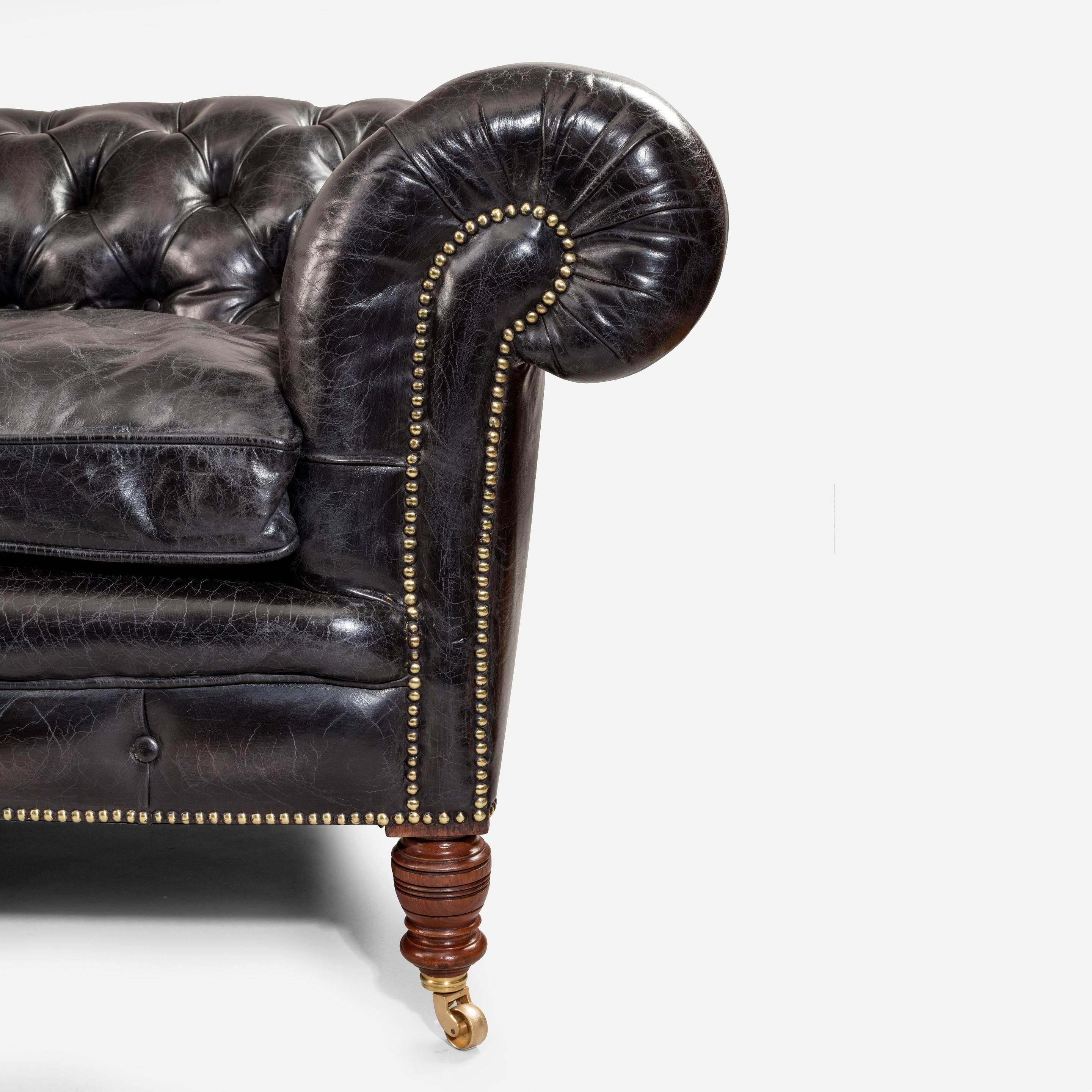 A fine late Victorian Chesterfield, of typical from with turned walnut legs and refurbished castors, reupholstered in deep buttoned distressed black leather.
