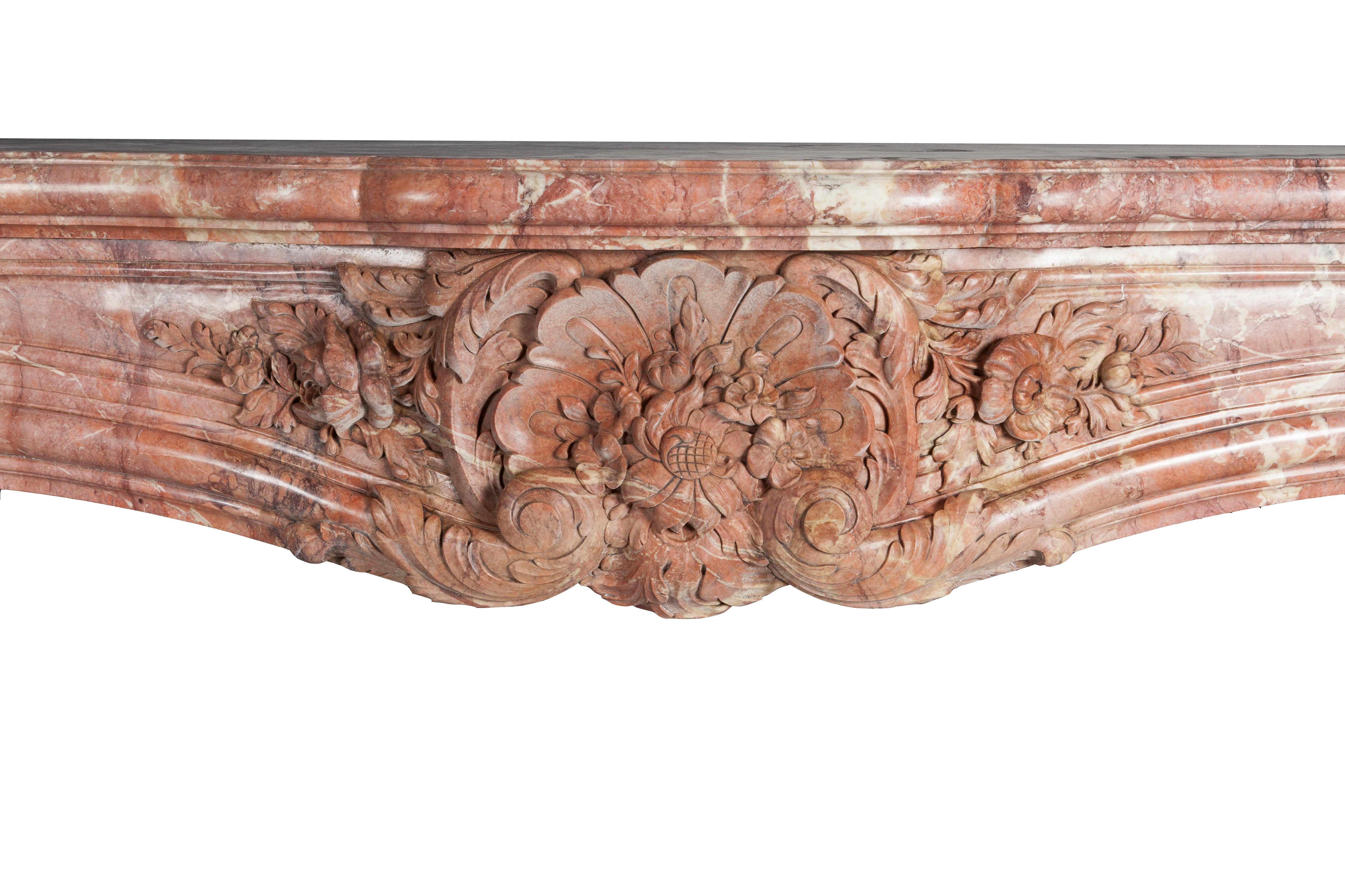 Important and massive  Louis XV fireplace model. Made in a unique old pink marble .
With serpentine-shaped shelf and bowed frieze, decorated by spring flowers in the center of the frieze and on both of the sides of the lintel. 
The sizeand