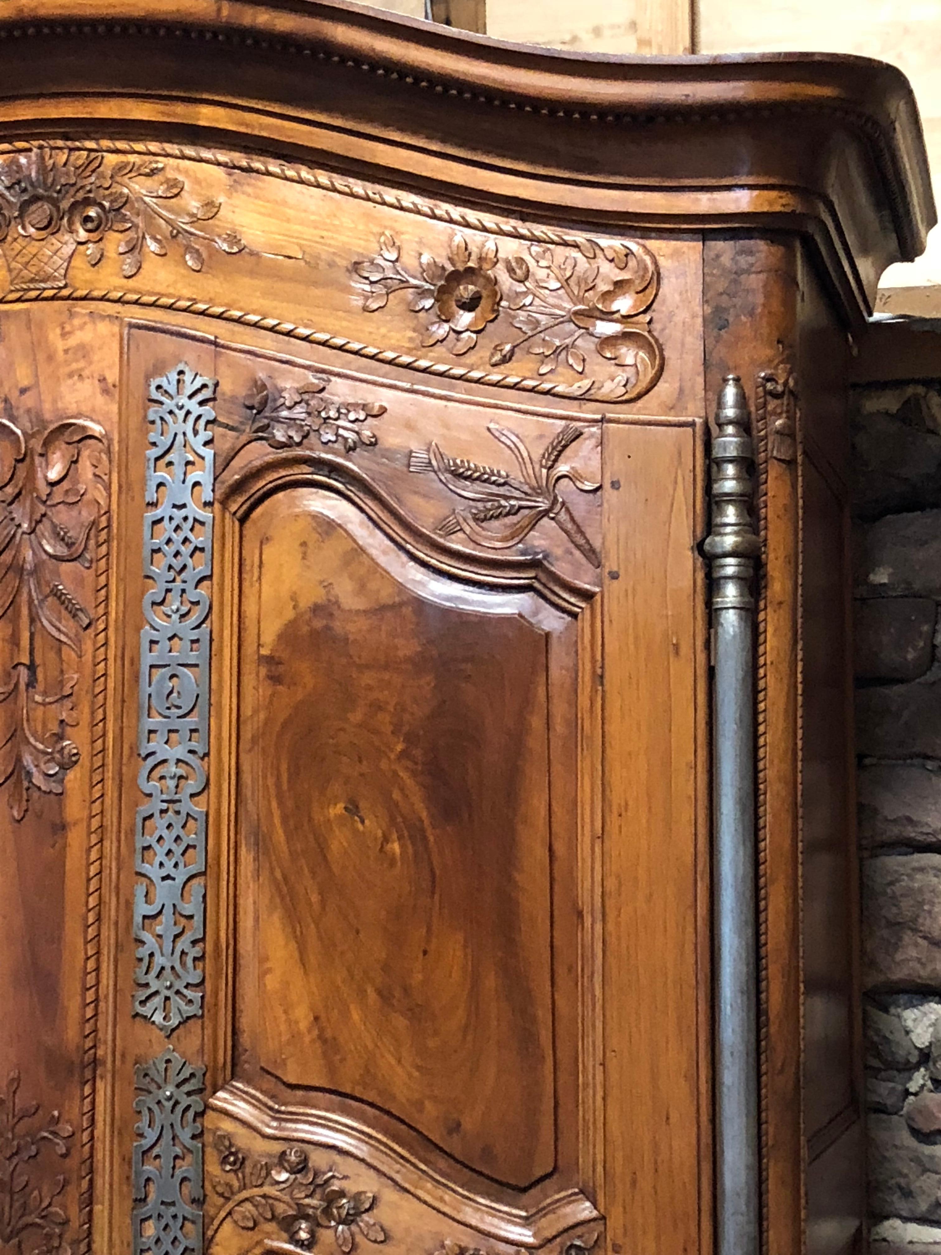 A museum quality Provencale Louis XV wedding armoire in walnut with beautifully carved and paneled doors, a chapeau gendarme cornice, great iron hardware, and carved cabriole legs. The armoire was part of a private collection assembled by the two