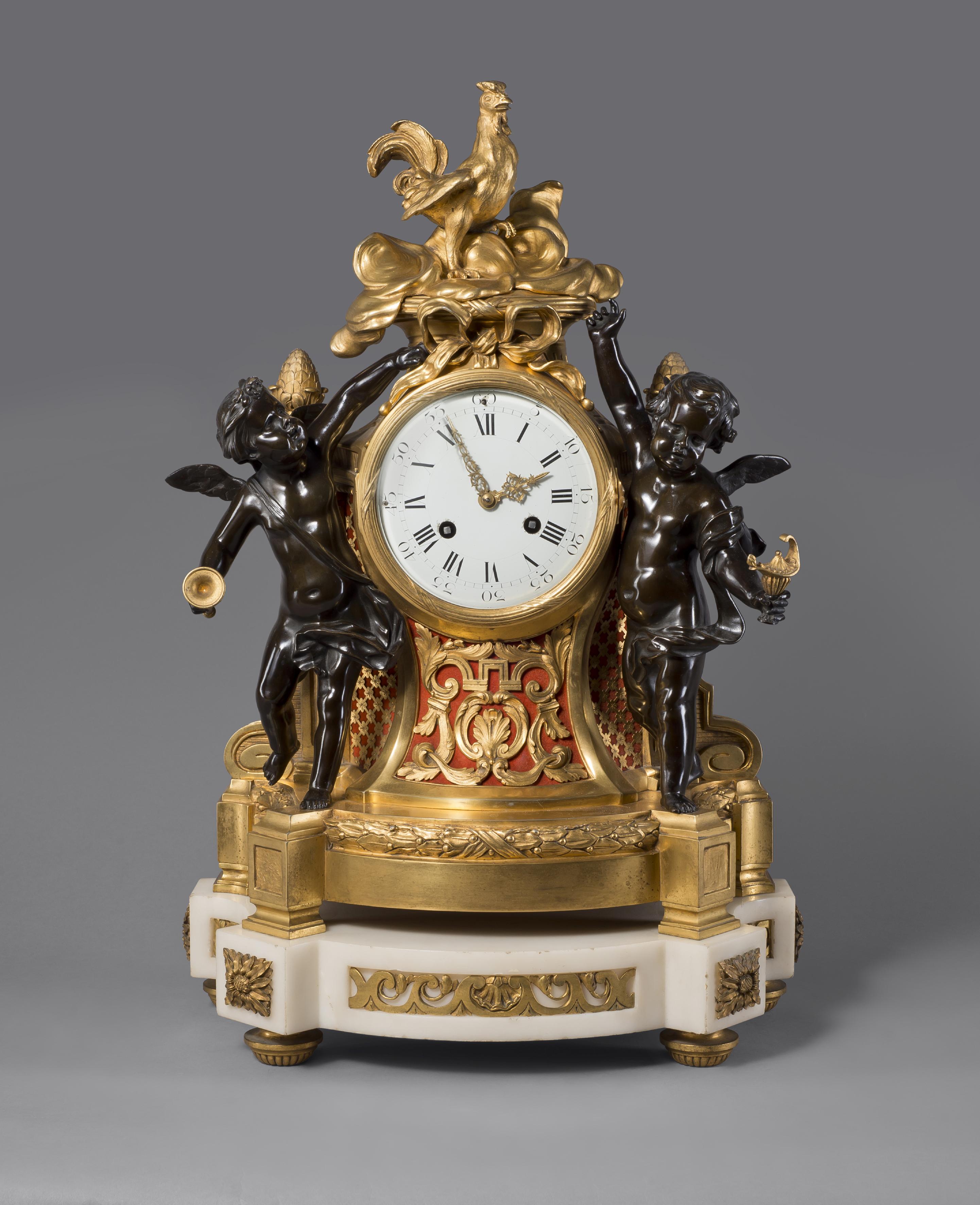 A fine Louis XVI style gilt and patinated bronze figural clock.

French, circa 1870.

This fine clock has a waisted body decorated with scrolls and trellis centred by a white enamel dial with Roman numerals surmounted by a cockerel and flanked