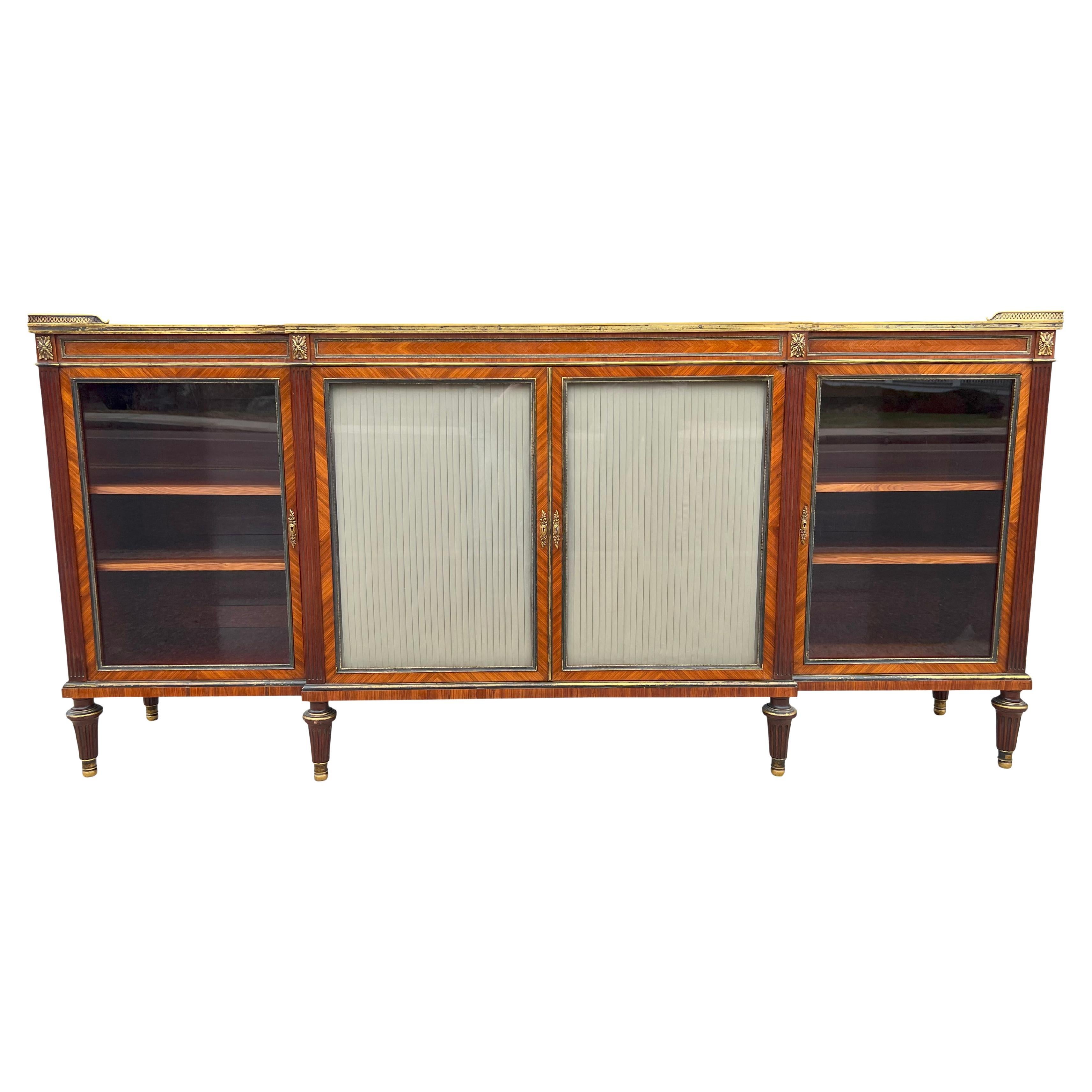 The best quality of construction. With rectangular breakfront form top with wonderfully figured kingwood with a cast bronze edge. Over a pair of pleated silk lined beveled glass doors enclosing shelves flanked by a pair of beveled glazed doors.