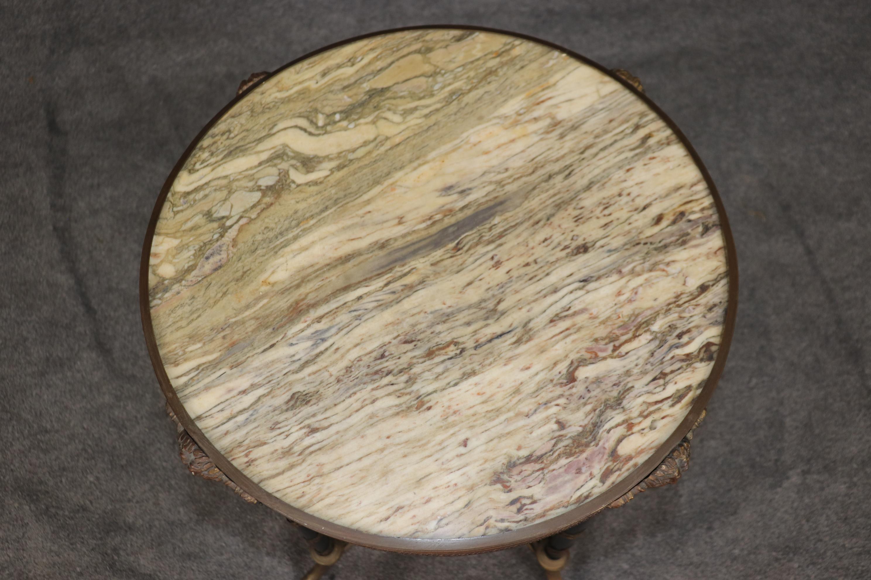 This is a superbly crafted end table in the manner of Adam Weisweiler with bronze ormolu wrapping around the legs and bronze face basques on the top. The table is in beautiful antique condition with its original marble and finish. The table dates to